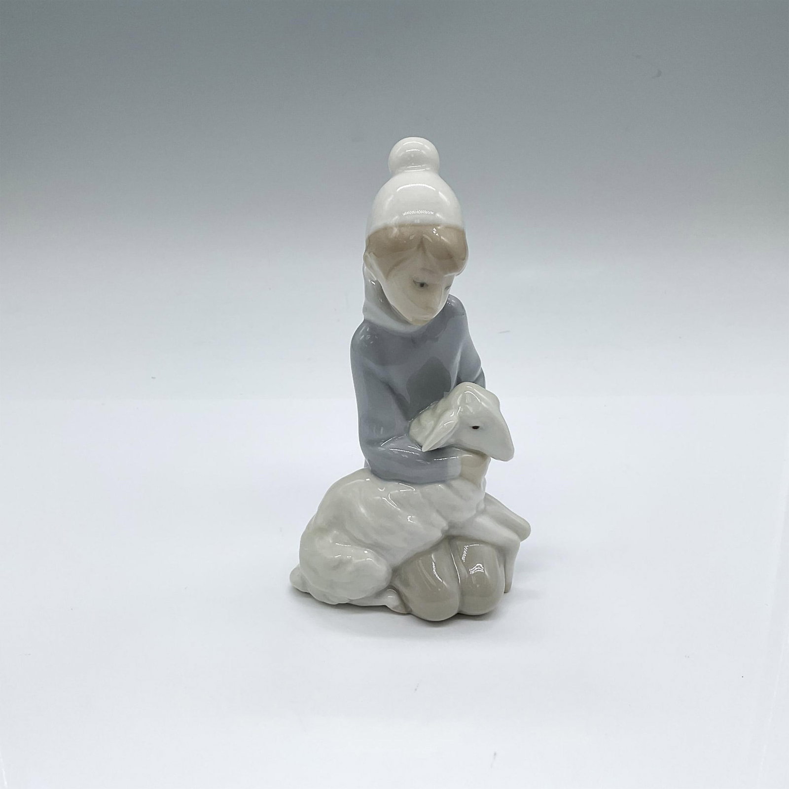 Shepherd With Lamb 1004676 - Lladro Porcelain Figurine: Glossy finish; Lladro backstamp. Artist: Juan Huerta Issued: 1969 - 2001 Dimensions: 3.25"L x 2.75"W x 5.75"H Manufacturer: Lladro Country of Origin: Spain