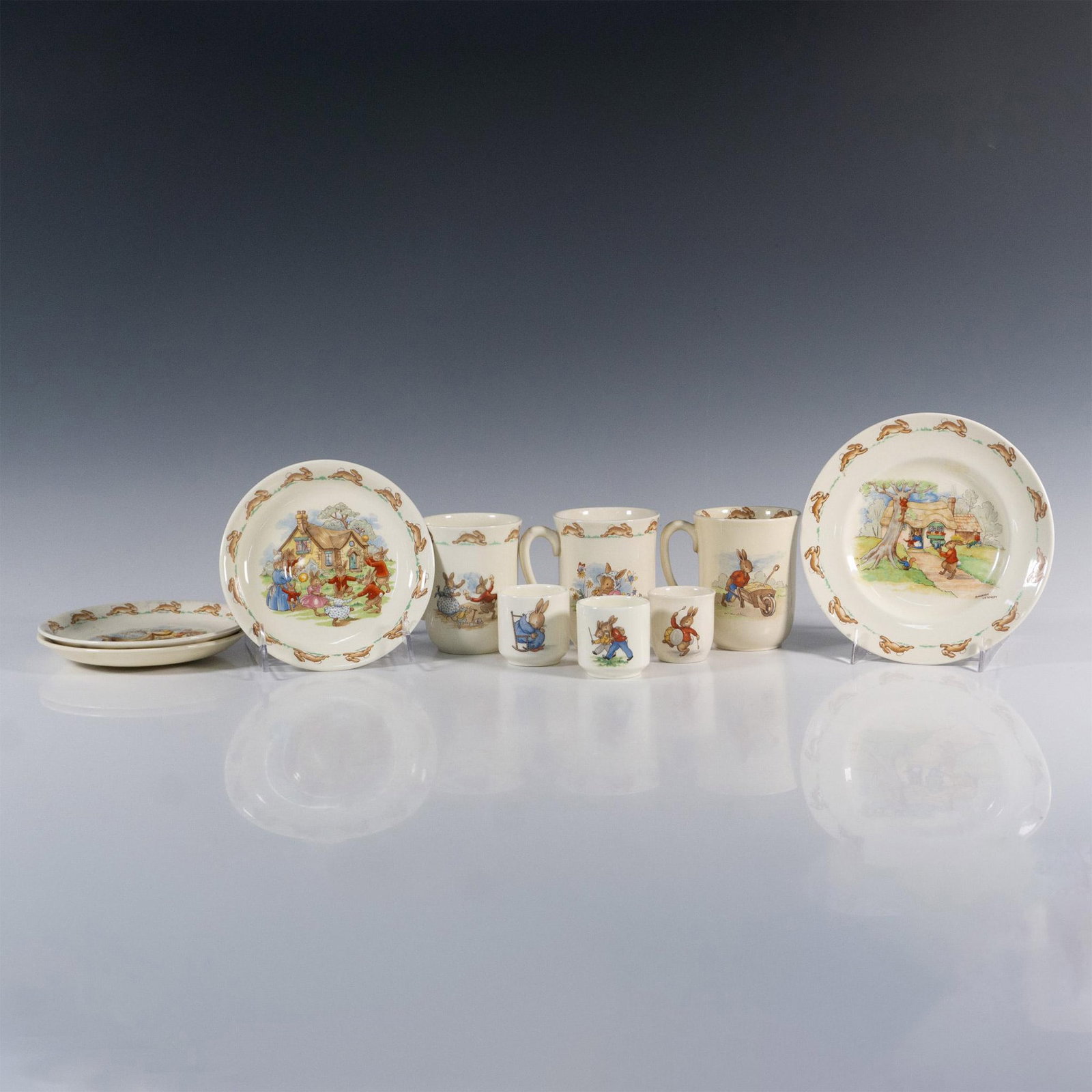 10pc Royal Doulton Bunnykins Mugs, Saucers & Egg Cups: Charming lot with traditional fun and playful Bunnykins scenes. Two mugs and two saucers, and the small plate are by Barbara Vernon. The three mugs measure 3.75"L x 2.75"W x 3.5"H. The three saucers m
