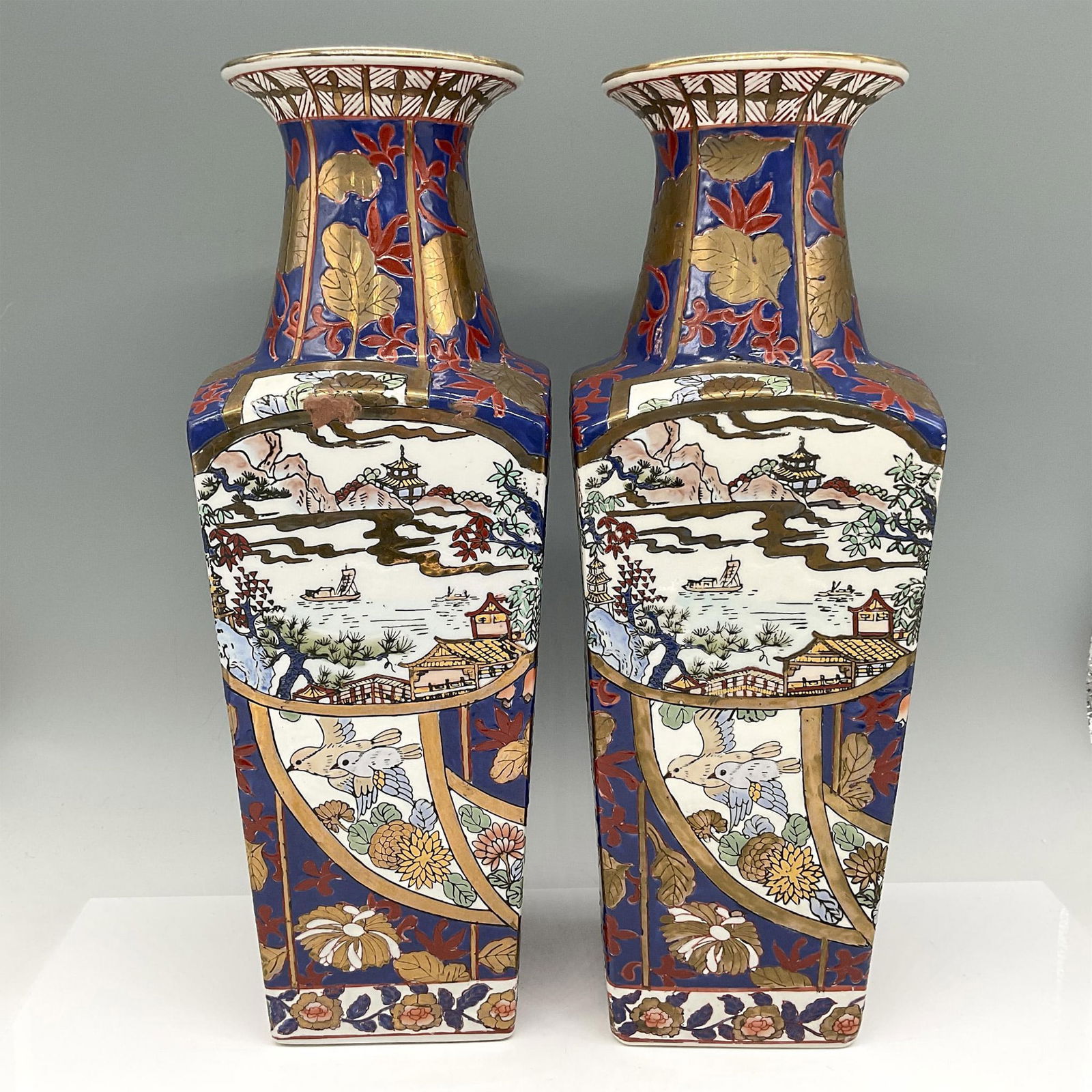 Pair of Vintage Chinese Porcelain Bird & Floral Vases: Hand painted and decorated in blue and rust coloration with gilt on rim and within design. Paneled, raised enameled scenes of bird, flowers, mountains and waterway. Logo syllabic backstamp. Issued: 20