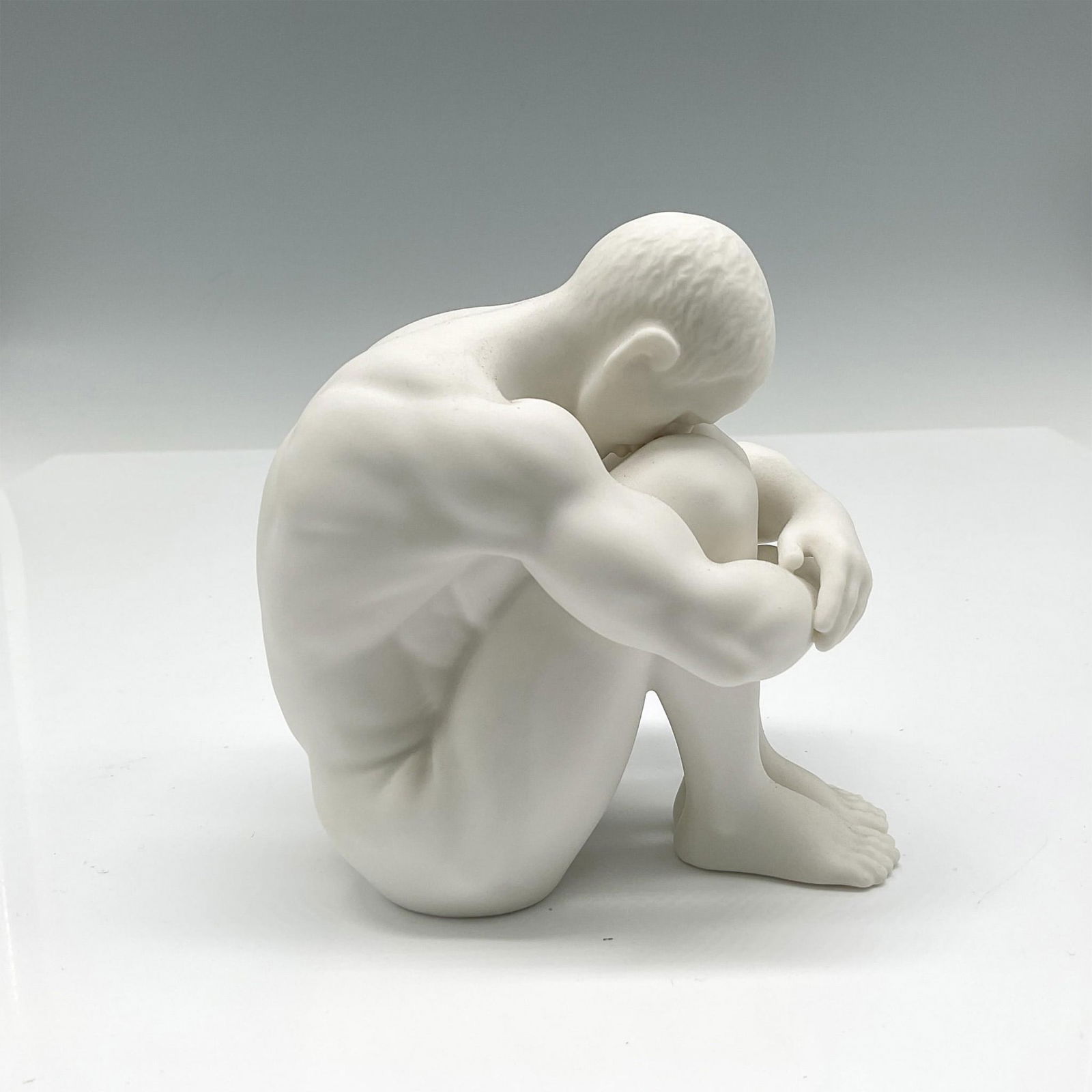 Unicorn Studio Porcelain Head Bowed Nude Male Figurine: Matte finished figural of nude male with legs to his chest, head bowed. Unicorn Studio mark. Issued: 21st century Dimensions: 3"L x 4.5"W x 4.75"H Manufacturer: Unicorn Studio Country of Origin: Unite