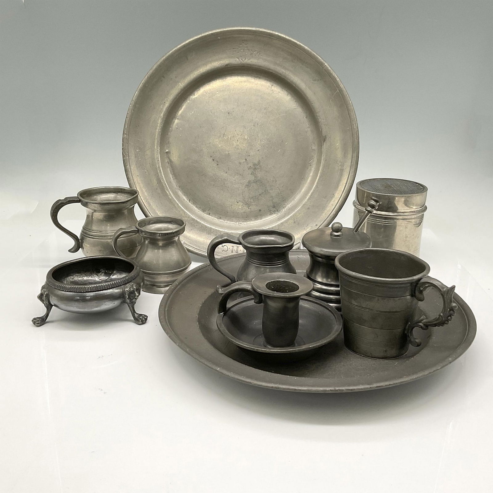 10pc Mixed Lot of English Silver Serveware: Lot includes 2 round plates, 3 small tankards, honey bowl, cup, candlestick holder, sifter and footed salt cellar. England impressed mark. Largest measures: 1"H x 10" dia. Issued: 20th century Country