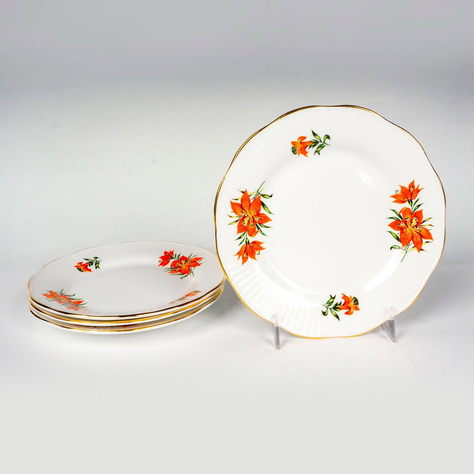 4pc Rosina-Queens China Tea Plates, Tiger Lily: Beautifully white plates with gilded trims, adorned with orange tiger lilies. Rosina-Queens backstamps. Issued: 20th century Dimensions: 0.75"H x 6.5"dia Manufacturer: Rosina-Queens Country of Origin: