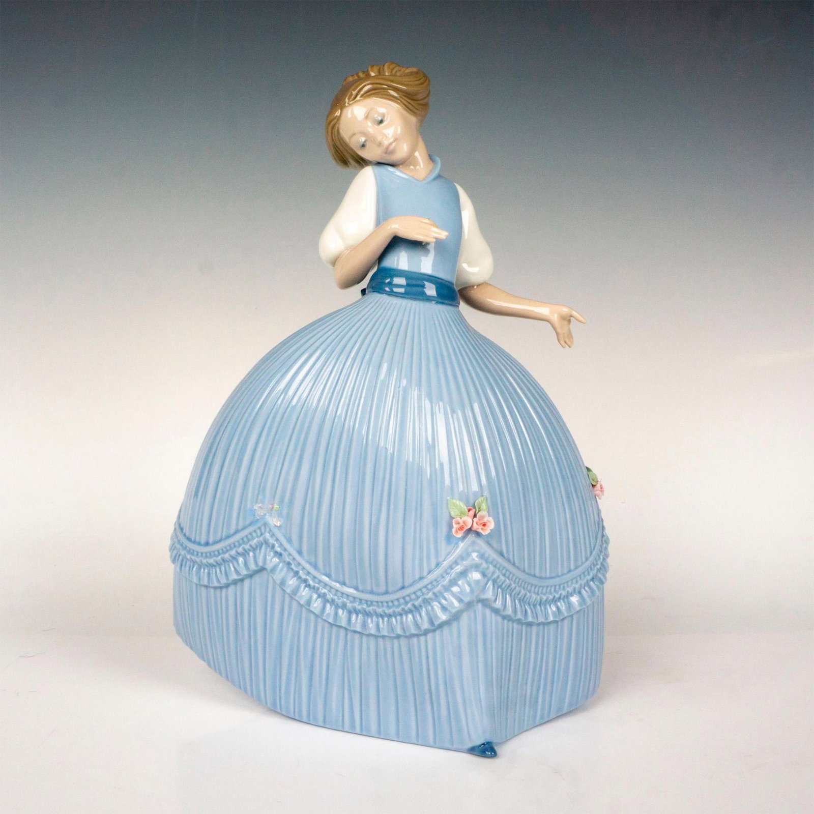 Girl In Blue Dress 1005121 - Lladro Porcelain Figurine: Glossy finish; Lladro backstamp. Artist: Jose Puche Issued: 1982 - 1985 Dimensions: 10.5"H Manufacturer: Lladro Country of Origin: Spain