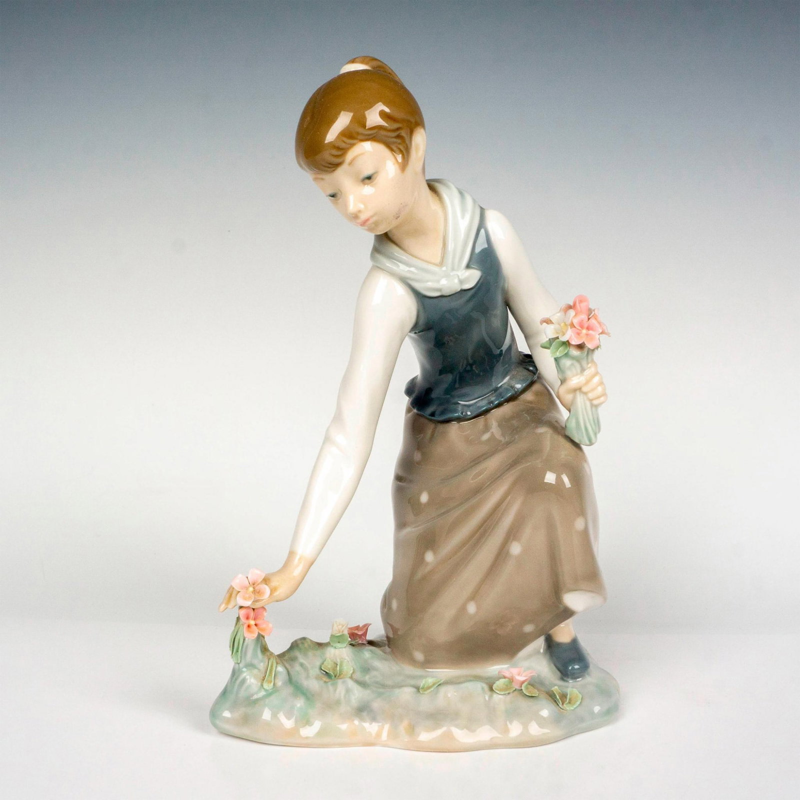 Girl With Flowers 1001172 - Lladro Porcelain Figurine: Glossy finish; Lladro backstamp. Artist: Vicente Martinez Issued: 1971 - 1993 Dimensions: 8.25"H Manufacturer: Lladro Country of Origin: Spain