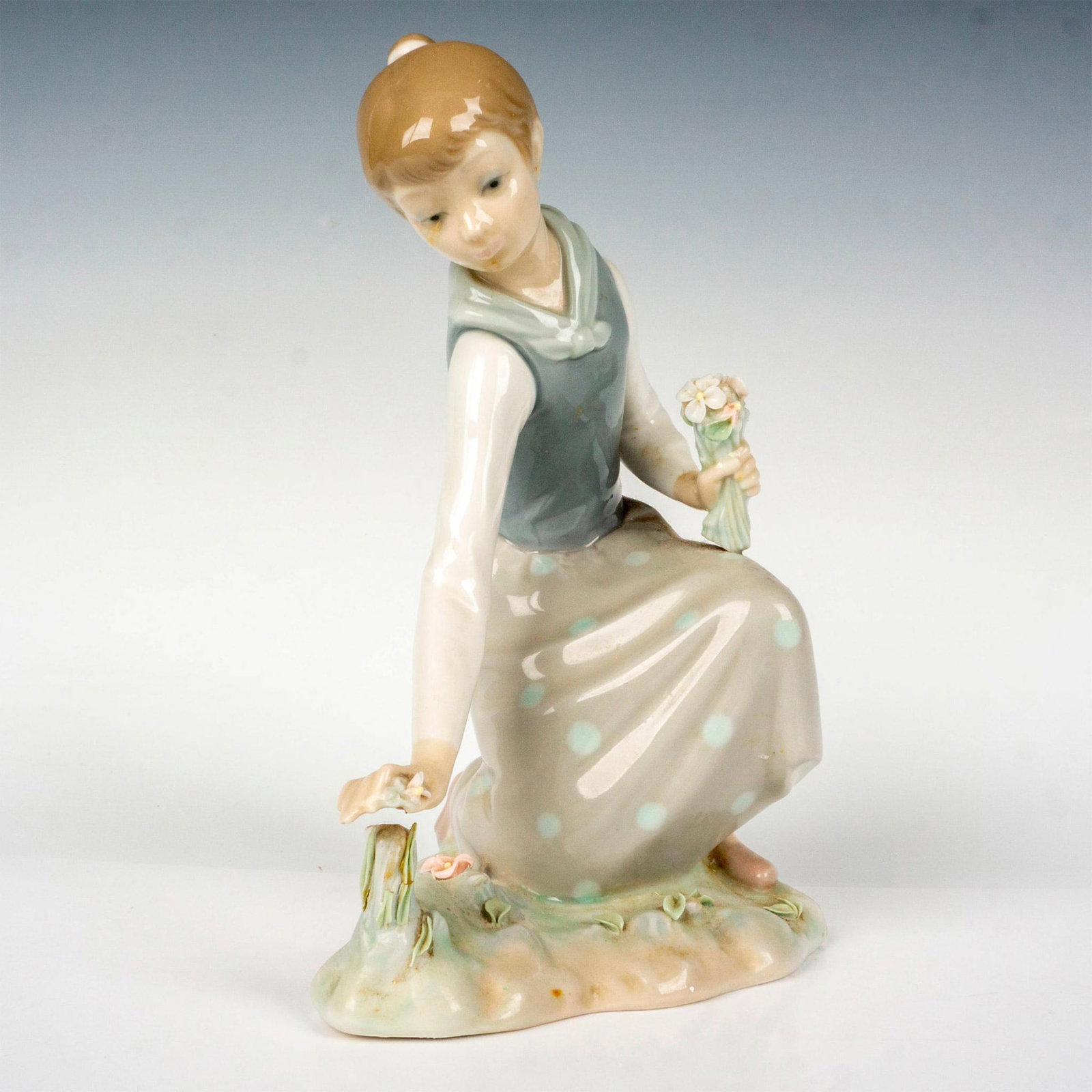 Girl With Flowers 1001172 - Lladro Porcelain Figurine: Glossy finish; Lladro backstamp. Artist: Vicente Martinez Issued: 1971 - 1993 Dimensions: 8.25"H Manufacturer: Lladro Country of Origin: Spain