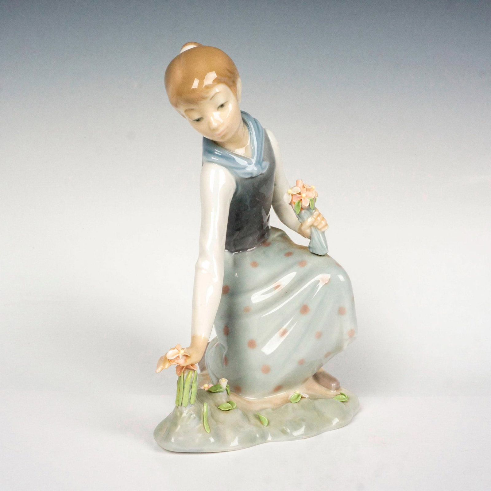 Girl With Flowers 1001172 - Lladro Porcelain Figurine: Glossy finish; Lladro backstamp. Artist: Vicente Martinez Issued: 1971 - 1993 Dimensions: 8.25"H Manufacturer: Lladro Country of Origin: Spain