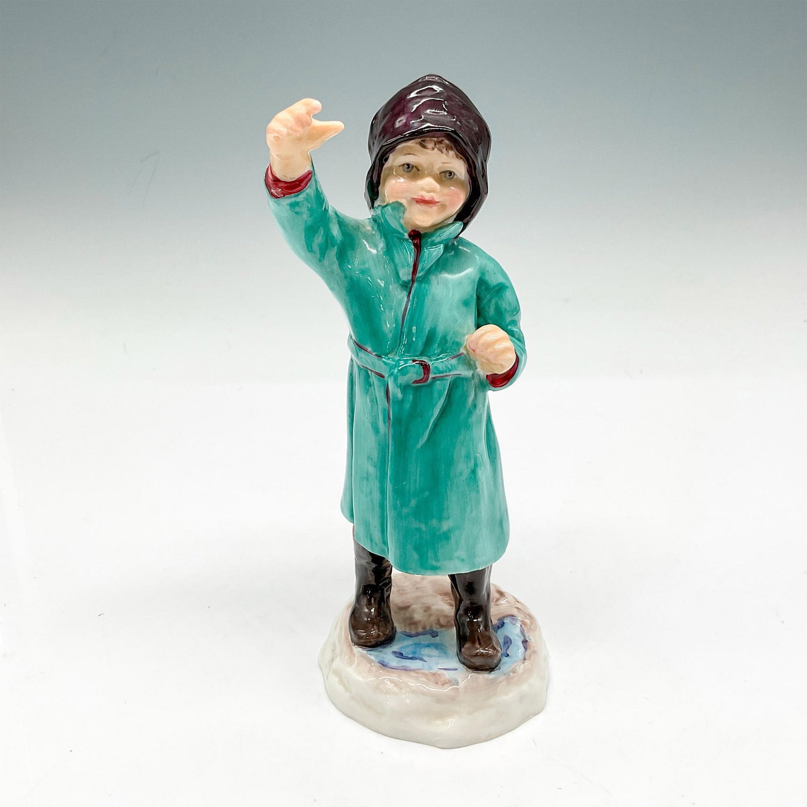 Royal Worcester Bone China Figurine, February: Young boy in green raincoat waving. Royal Worcester backstamp. 3453. Issued: 20th century Dimensions: 2.5"L x 2.5"W x 6.5"H Manufacturer: Royal Worcester Country of Origin: England