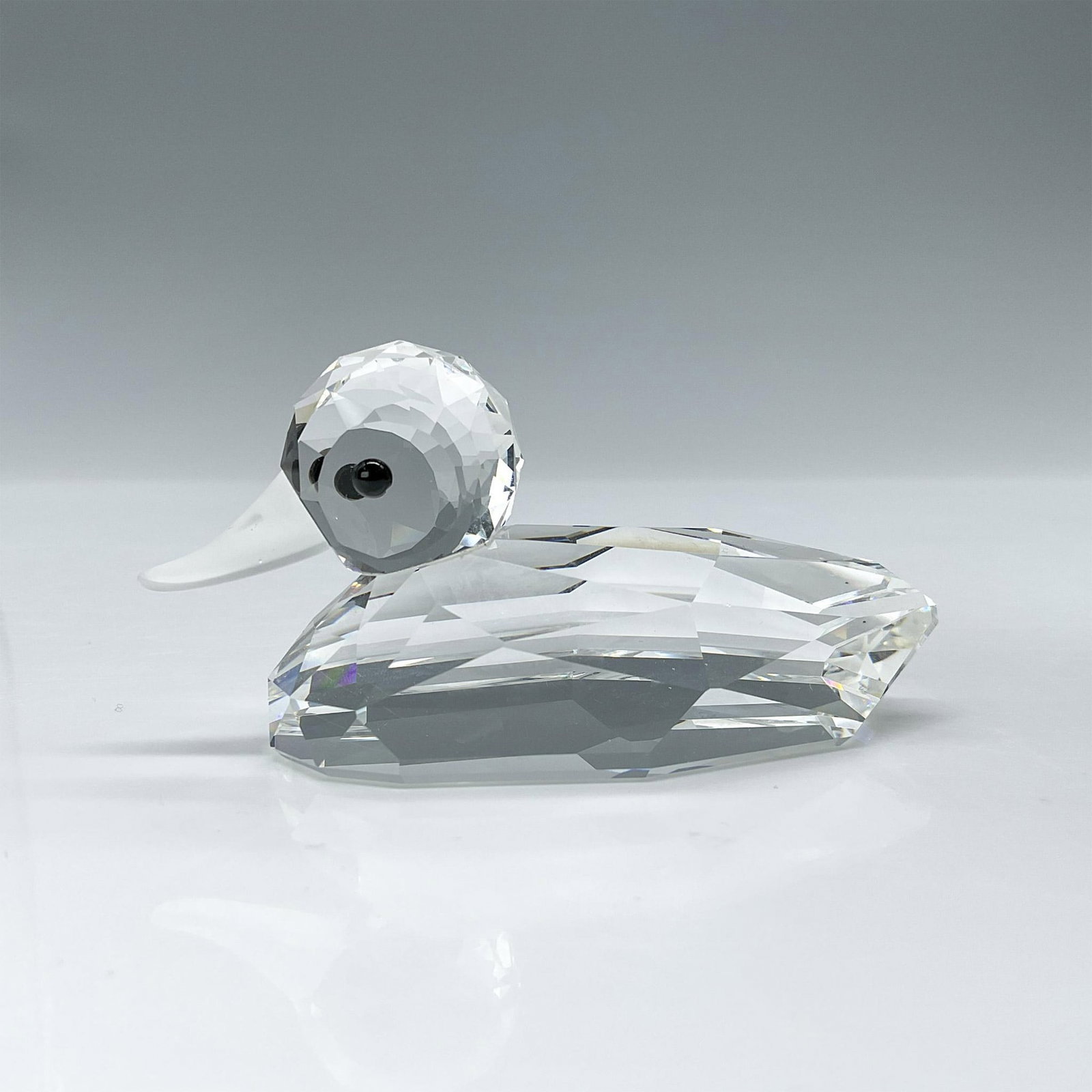 Swarovski Crystal Figurine, Duck: This rare duck features a faceted clear crystal body with frosted bill and thoughtful black eyes. Swarovski etched backstamp. This item has its original box which measures 5"H x 3.25" dia. Dimensions: