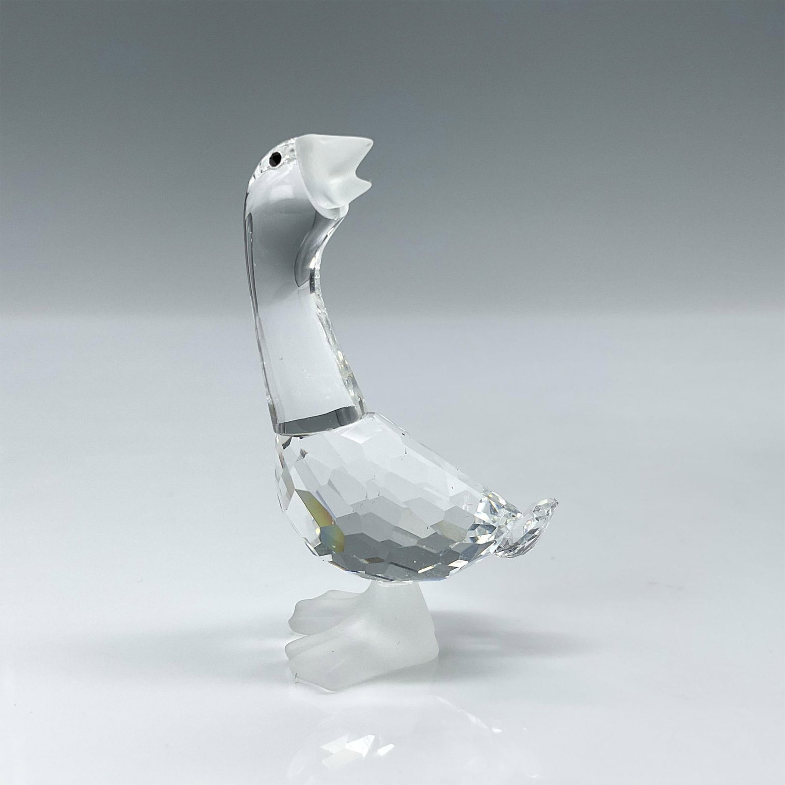 Swarovski Silver Crystal Figurine, Goose Dick: A clear faceted goose, with black eyes and frosted beak and feet, gazes back and upward. Swarovski mark. This item has its original box: 2.5"H x 3.25" dia. Dimensions: 1.25"L x 0.75"W x 0.75"H Manufac