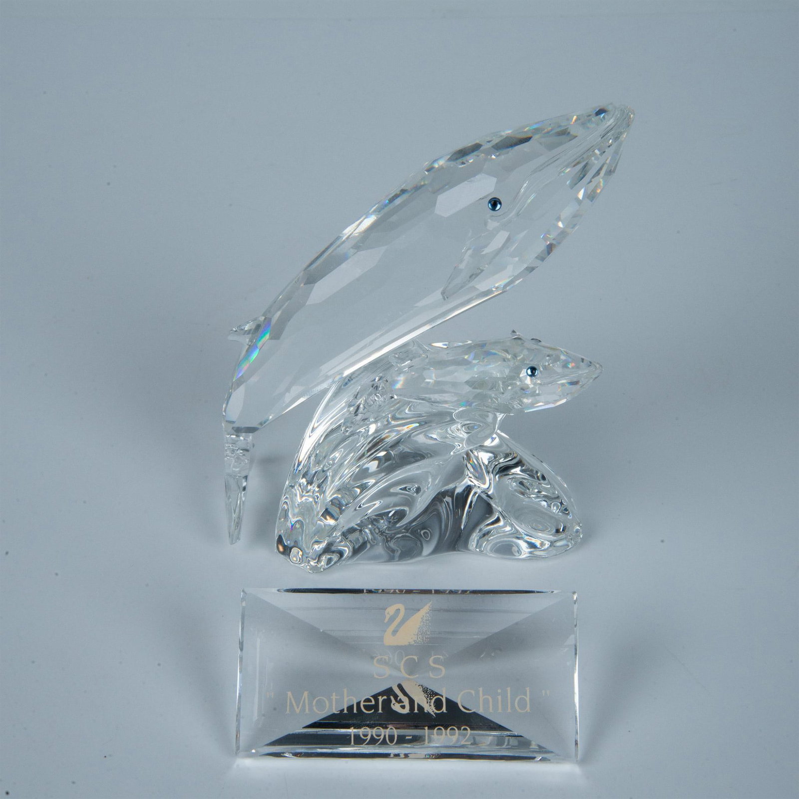 2pc Swarovski Crystal Care for Me Whales + Plaque: Crystal figural of Humpback whale mother and child cresting on a wave. Both stares out with blue crystal eyes. 164614. SCS Mother and child 1990 - 1992 Plaque. Swarovski backstamp. Artist: Michael Sta