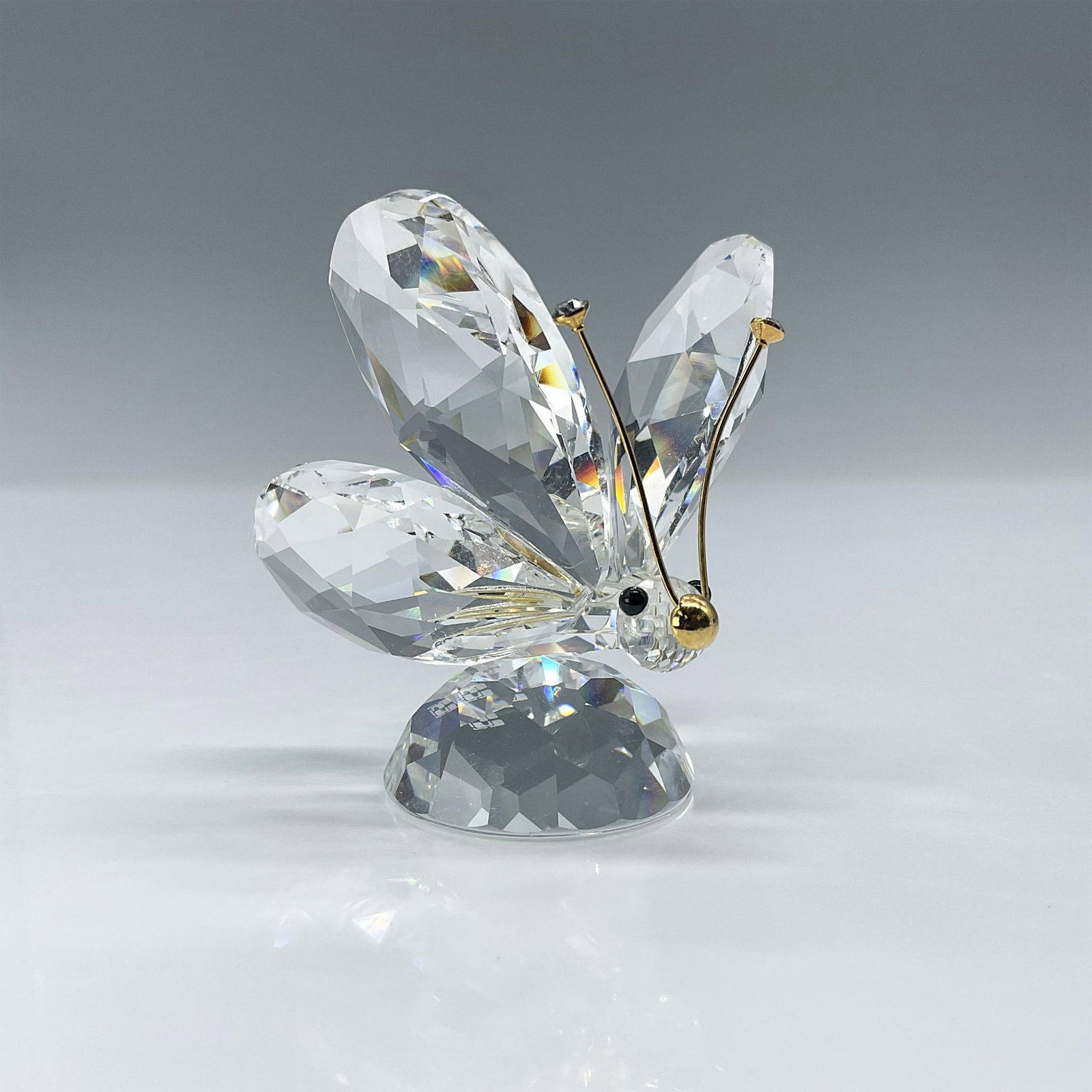 Swarovski Crystal Figurine, Butterfly with Gold Antennae: Spectacular clear crystal butterfly with crystal tipped gold antennae. Swarovski etched backstamp. Issued: 1982-2006 Dimensions: 2"L x 1.75"W x 2.25"H Manufacturer: Swarovski Country of Origin: Austri
