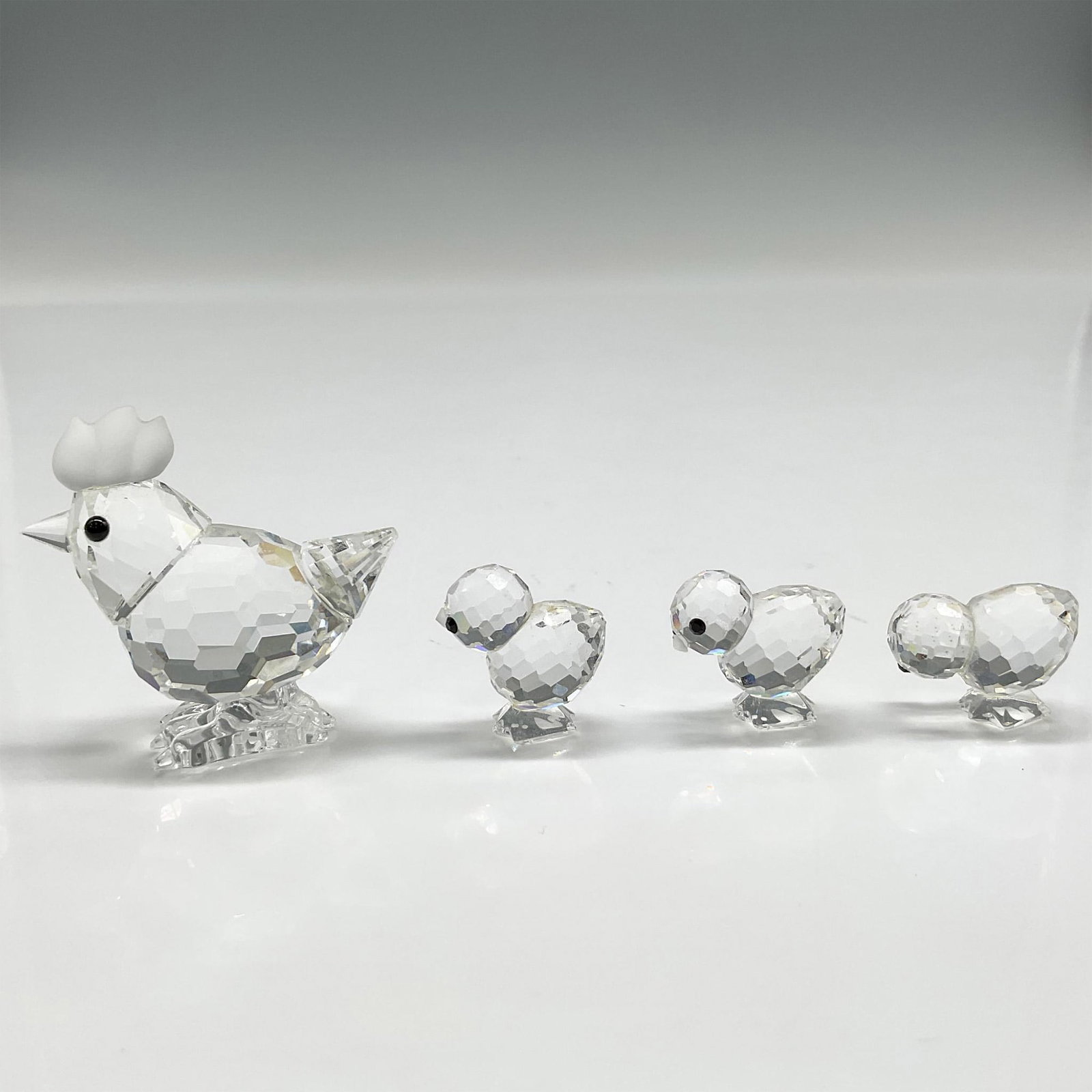 4pc Swarovski Crystal Figurine, Hen and Chicks: Adorable crystal family is part of the Barnyard Friends group. All created in clear faceted crystal with black crystal eyes. Mother hen has frosted comb. Swarovski backstamp. 014492. 014824. Artist: G