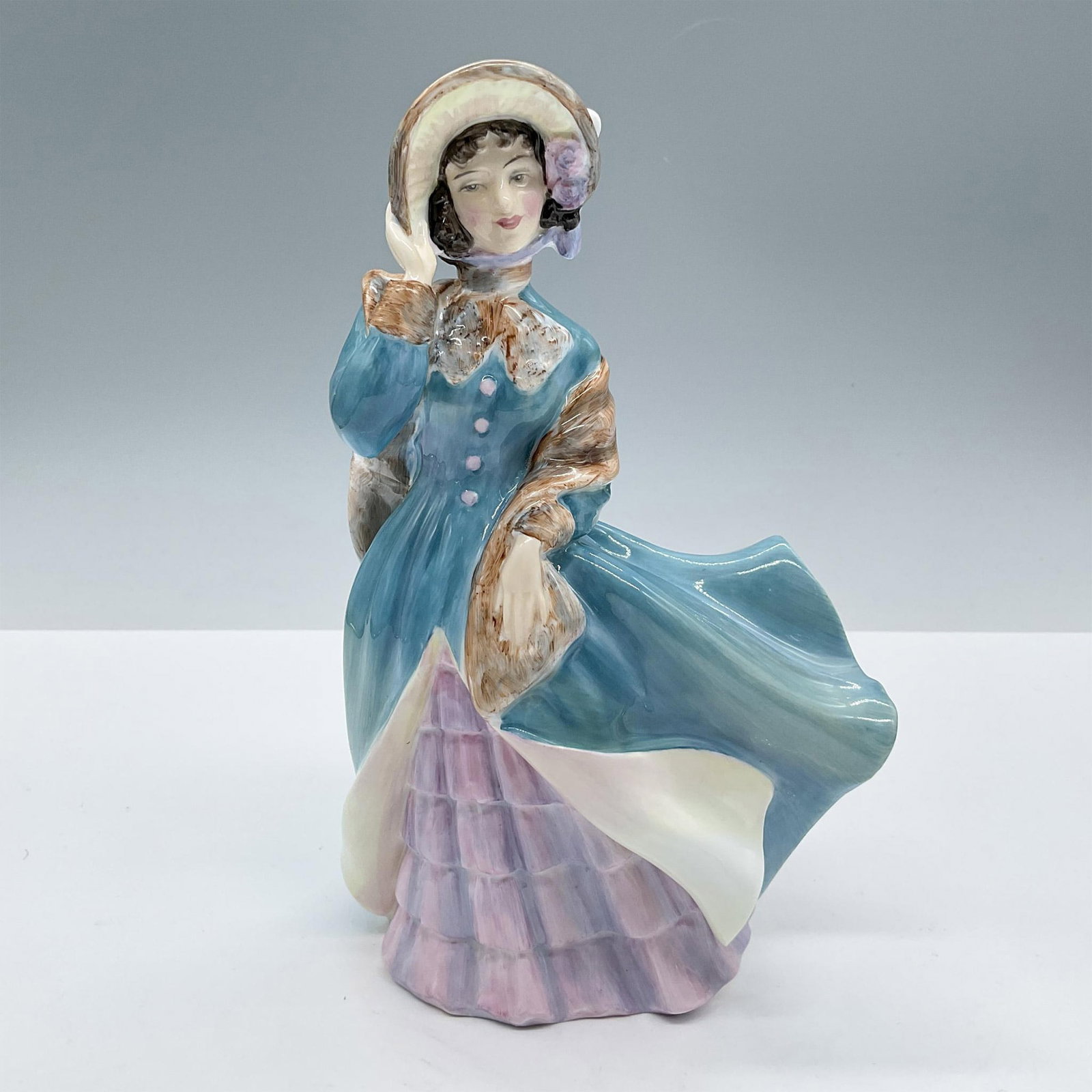 Delphine - HN2136 - Royal Doulton Figurine: From the Royal Doulton Pretty Ladies collection. Features a lady dressed in an elegant teal and pink dress completed by a brown fur scarf. Royal Doulton backstamp. Artist: Peggy Davies Issued: 1954 - 