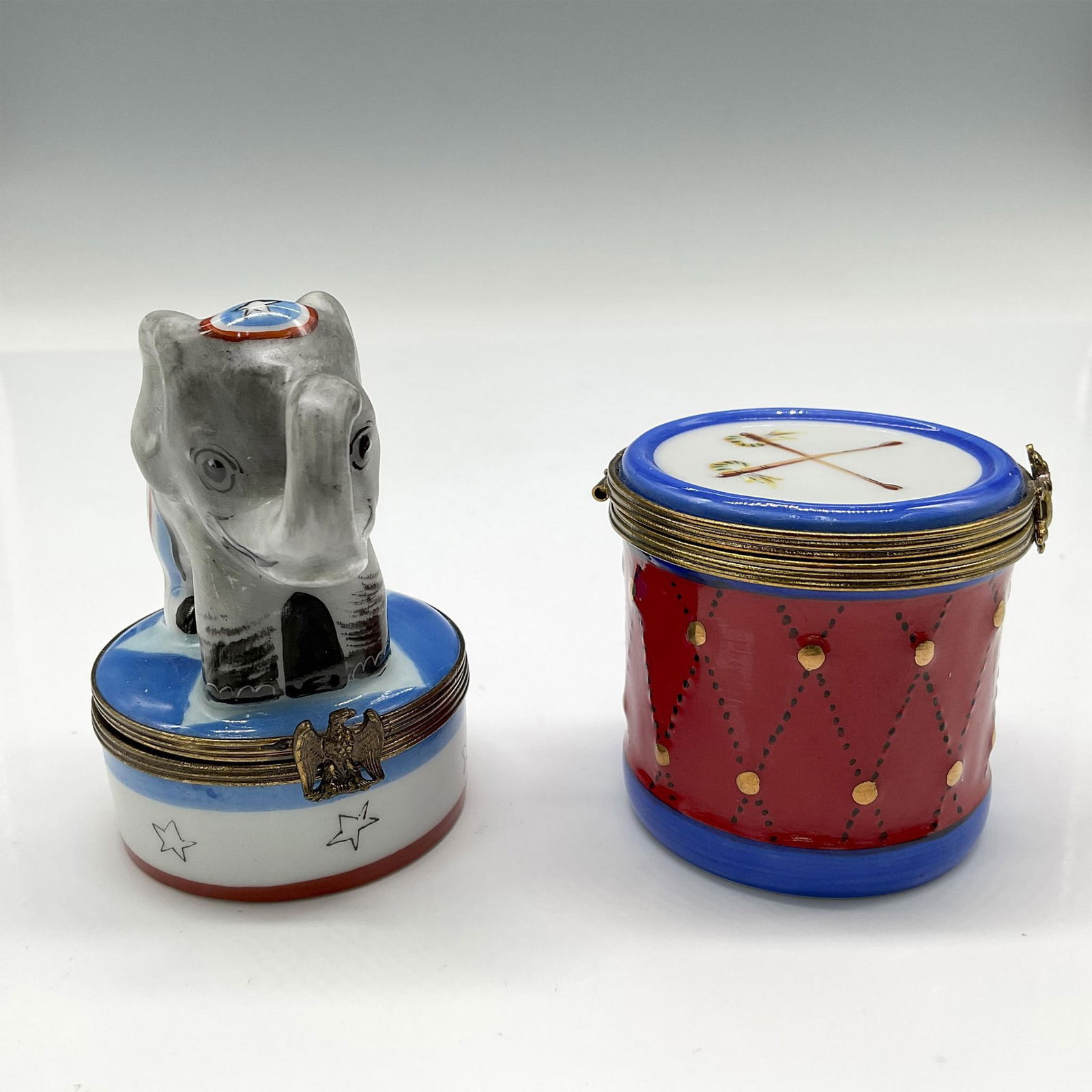 2pc Limoges Peint Main Porcelain Elephant & Drum Pill Box: Adorable patriotic Chamart figure 3"H, colored in red, white and blue with stars and stripes motif. Eagle clasp opens to blue leaf. Drum 2"H with metal band and bear clasp closure. Colored in red, whi