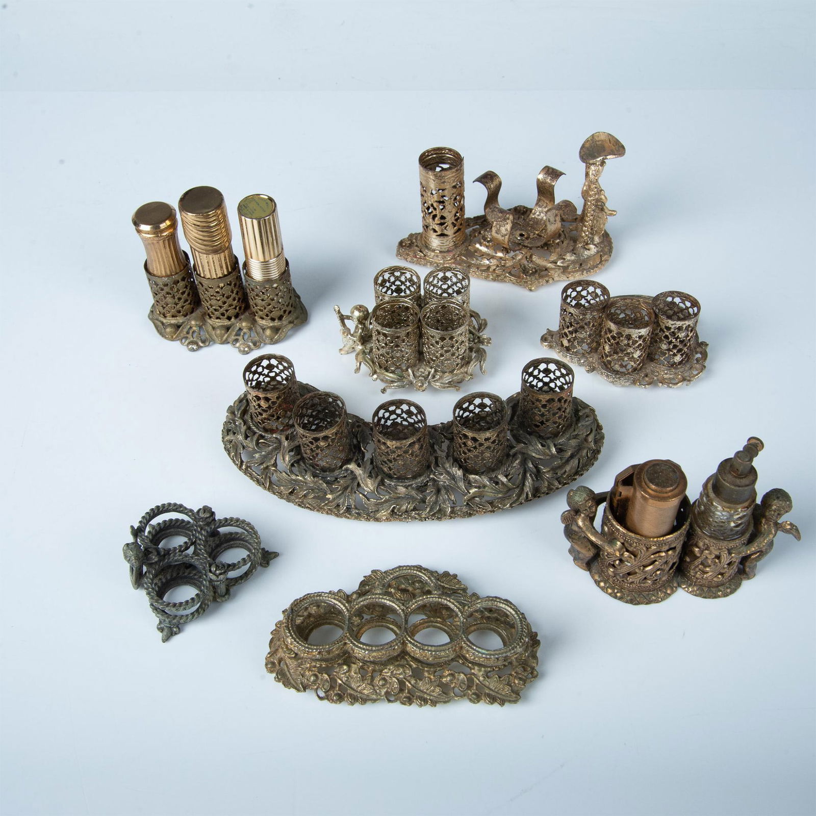 13pc Ornate Metal Vanity Makeup Organizers: This lot includes eight organizers with spots for various items. There are also four lipstick cases and a perfume bottle. The largest item measures approximately 6.75"L x 2"W x 1.75"H. Dimensions: See