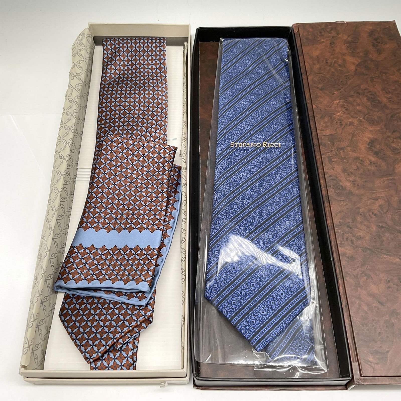 2pc Stefano Ricci and Brioni Silk Ties: Red and blue patterned tie with matching pocket scarf, 58"L - Brioni mark. This item has its original box: 15"L x 5"W x 1.25"H. Cobalt blue with black stripes and vine design - 58"L - Stefano Ricci in
