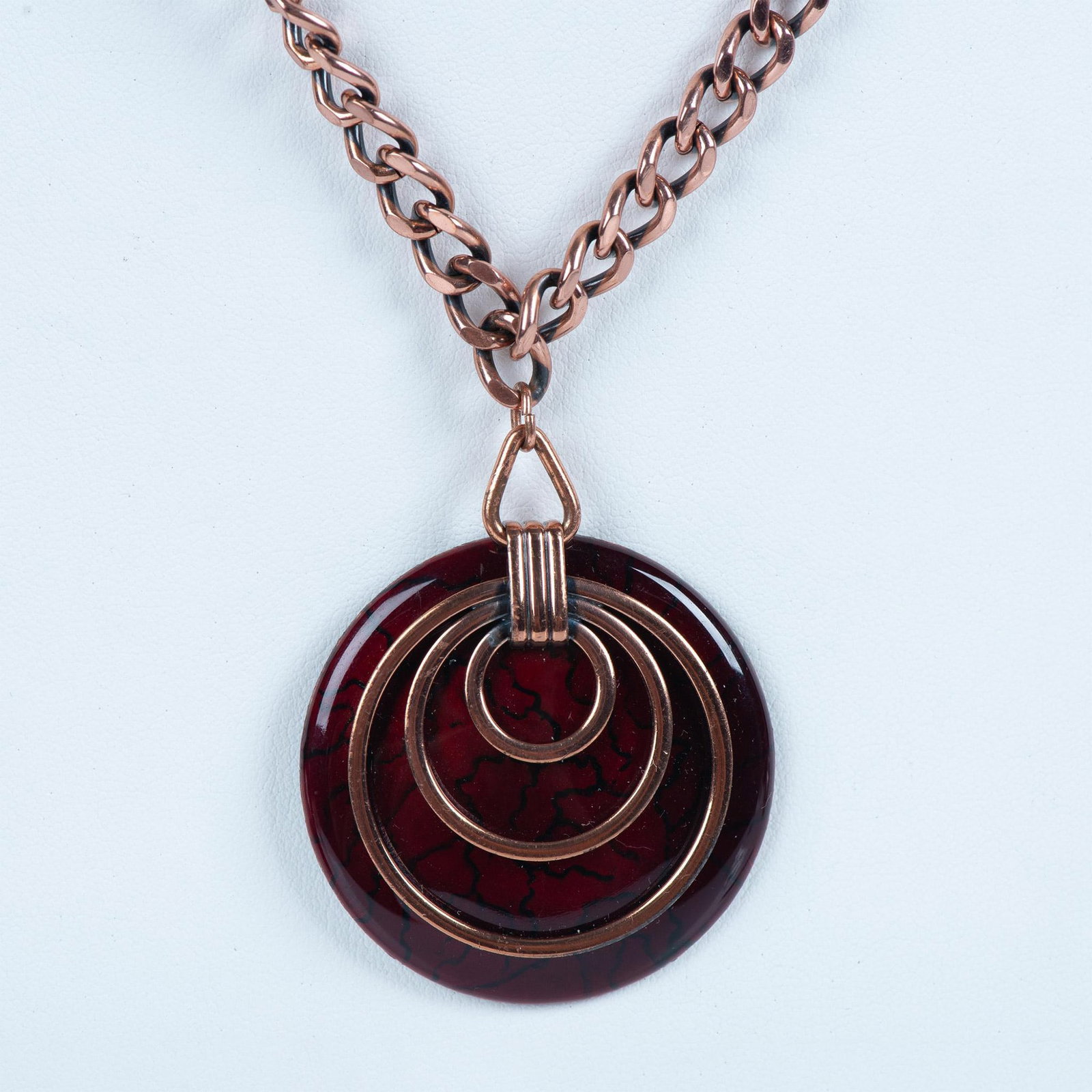 Matisse Copper Tortoise Like Saturn Necklace: This striking necklace is a disc shape of cognac color enamel over copper. There are thin swirls of copper applied on the front of the disc to form a Saturn like design. The pendant is attached to a n