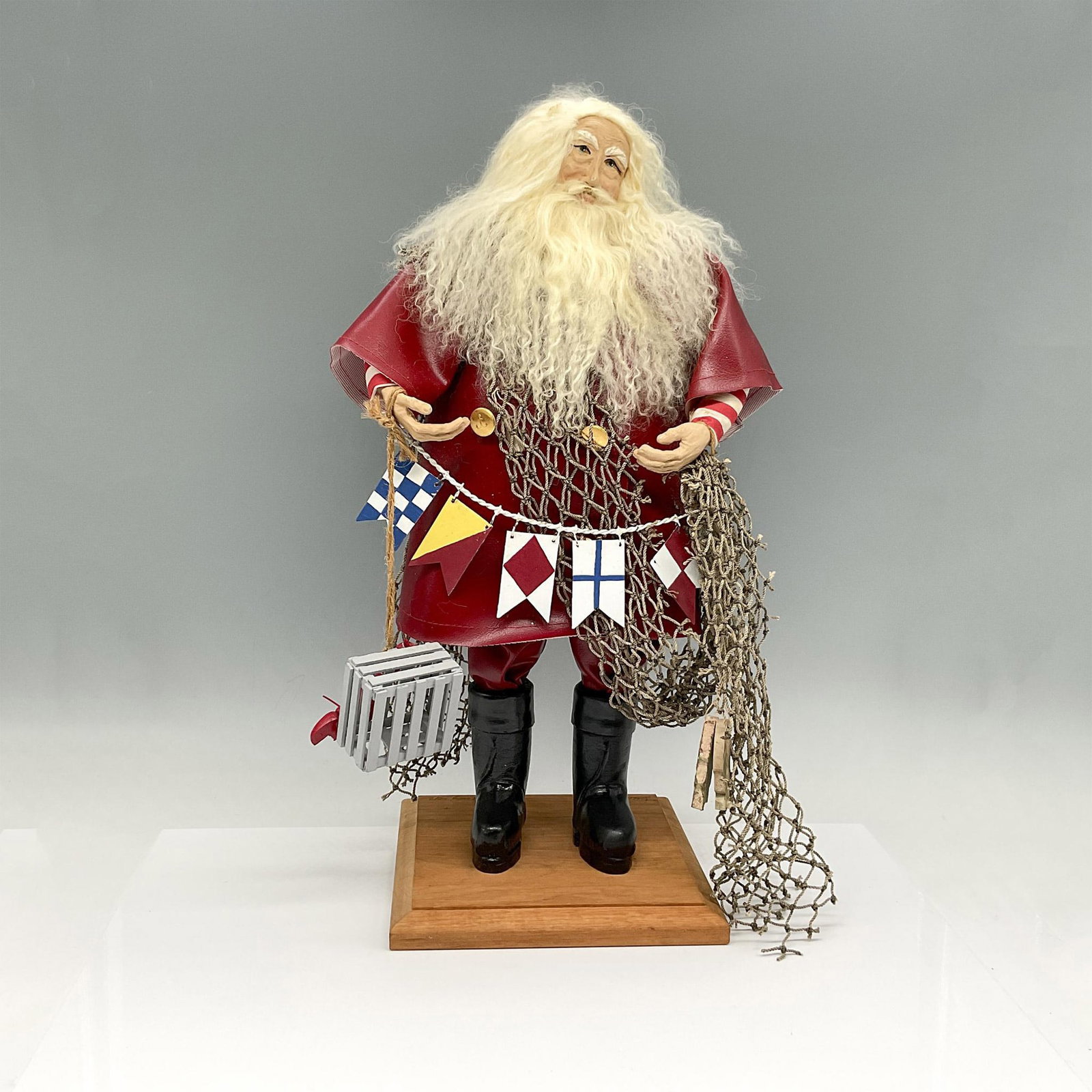 Lynn Haney Collections, Seaside Santa, Signed: This Santa will be visiting coastal towns. Holding his net and multi flag emblem, wearing black boots and rain gear. Lynn Haney Collections mark. Issued: 1992 Dimensions: 7"L x 7"W x 18"H Manufacturer