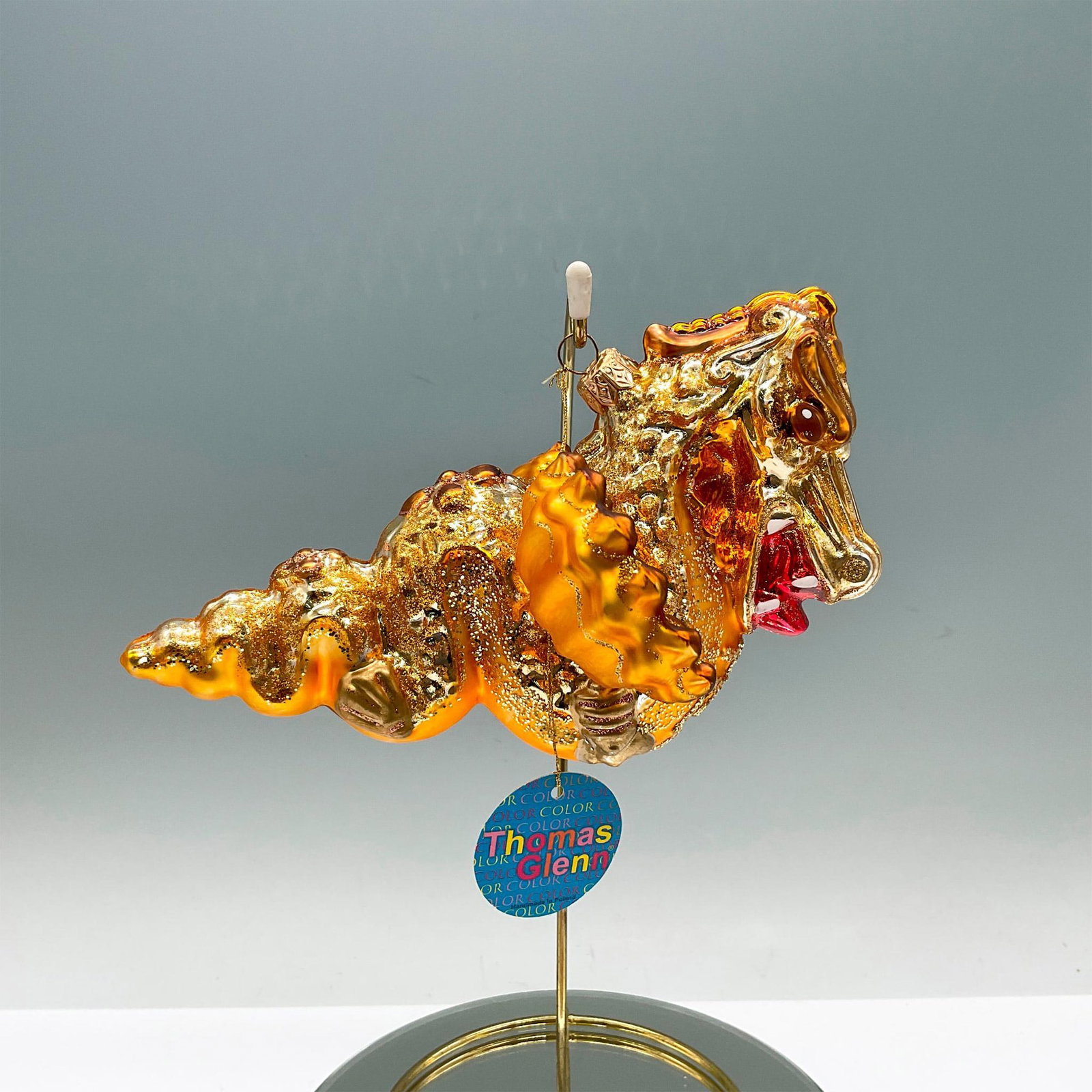Vintage Thomas Glenn Polish Ornament, Flying Dragon: A glittery amber-yellow Christmas tree ornament of a fierce Asian dragon. Original Thomas Glenn tag. Dimensions: 6.5"L x 4.5"W x 4.25"H Manufacturer: Thomas Glenn Country of Origin: Poland