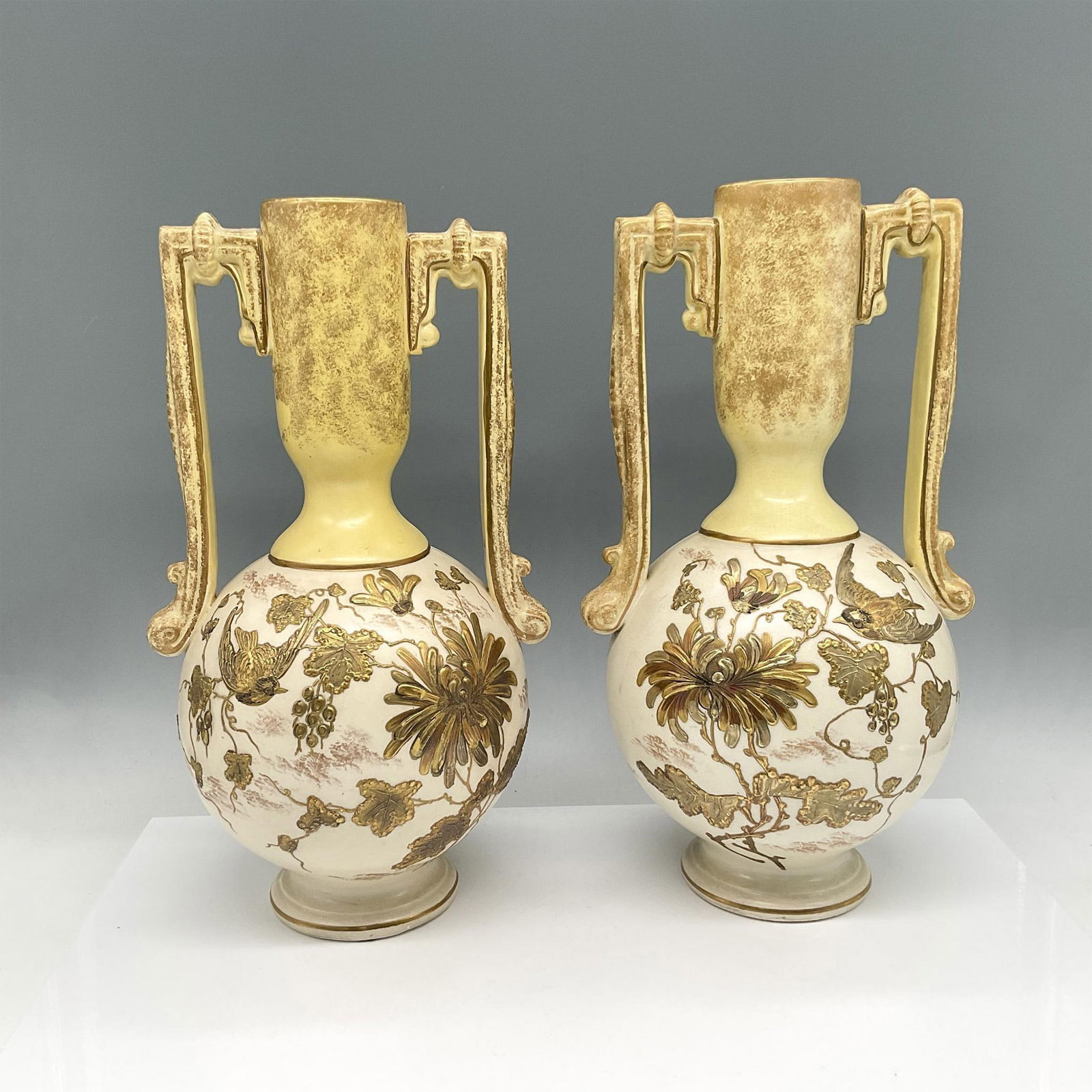 Pair of Thomas Forester & Sons Amphora Gilt Vases: Raised gilt design of birds and florals against yellow ground. Thomas Forester & Sons backstamp. Issued: Late 1880s Dimensions: 6"L x 6"W x 13"H Manufacturer: Thomas Forester & Sons Country of Origin: