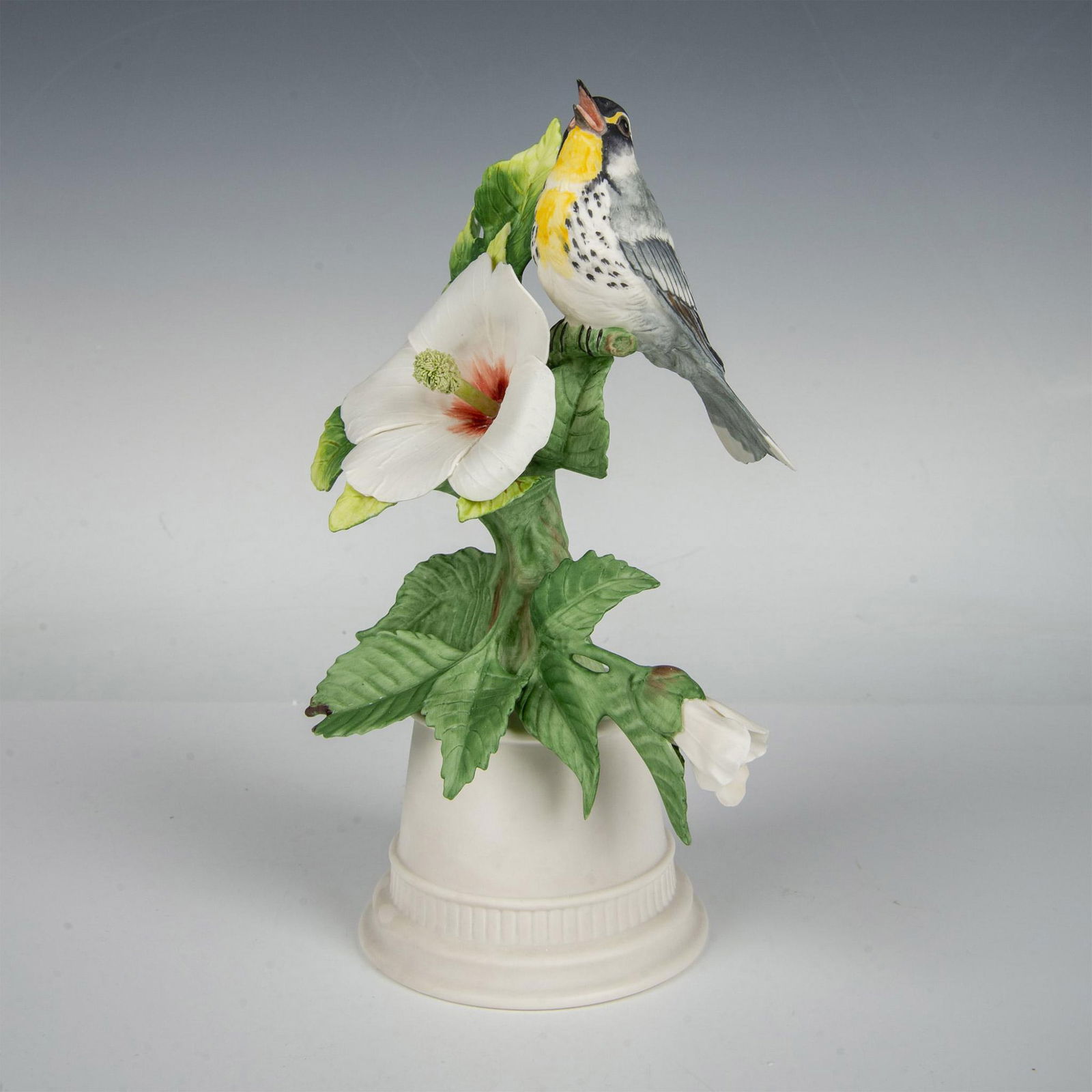 Boehm Porcelain Sculpture, Yellow-Throated Warbler 431: Beautiful naturalistic hand painted and hand crafted figure of a small bird perched on a white blossomed hibiscus. Boehm marked. Issued: 20th century Dimensions: 5.75"L x 5"W x 9.25"H Manufacturer: Bo