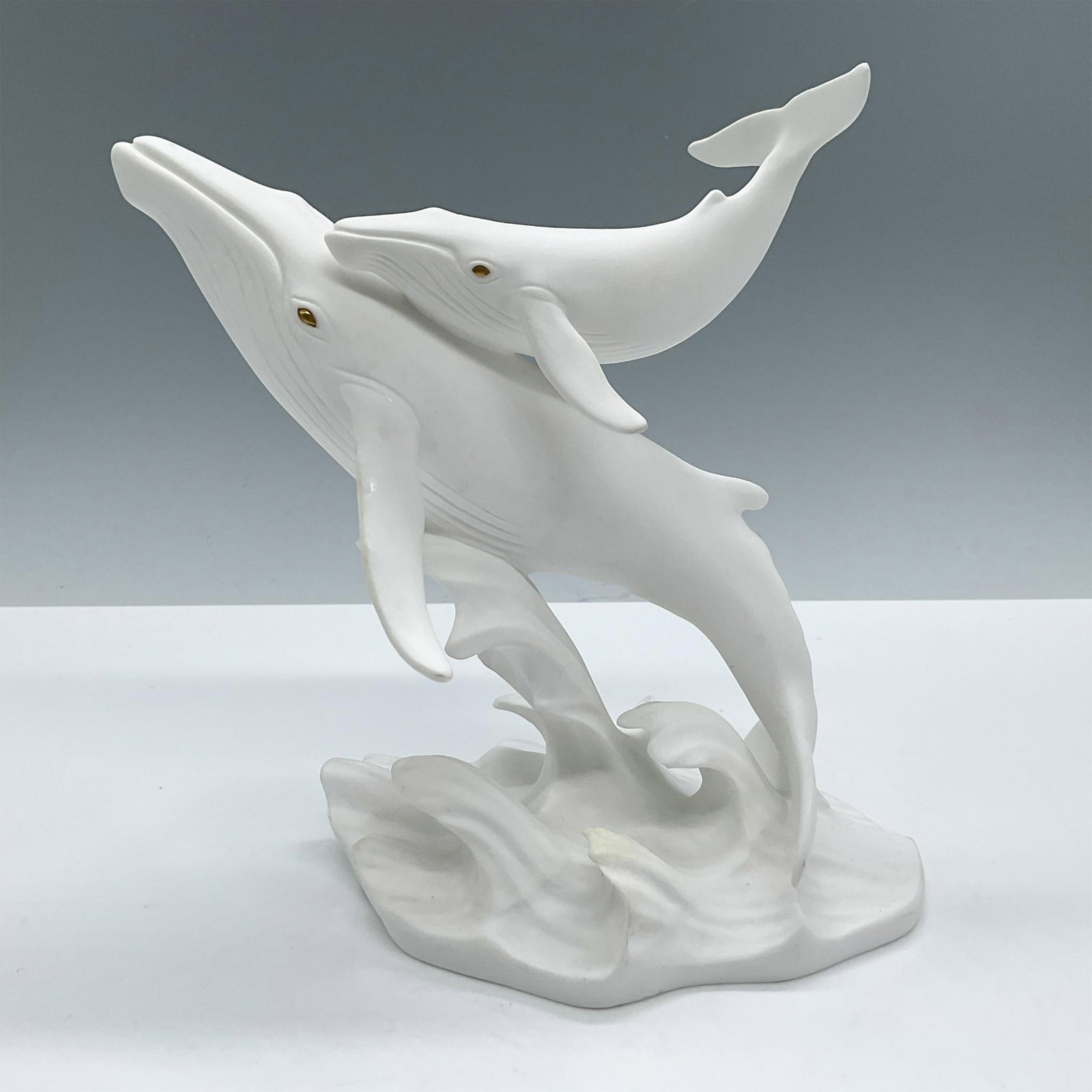Lenox Fine Bone China Figurine, Song of The Wales: Depicts a majestic scene of a whale and its calf, featuring gold eyes and a white matte finish. Lenox backstamp. Artist: Susan Lordi Issued: 1992 Dimensions: 4''L x 6''W x 7''H Manufacturer: Lenox