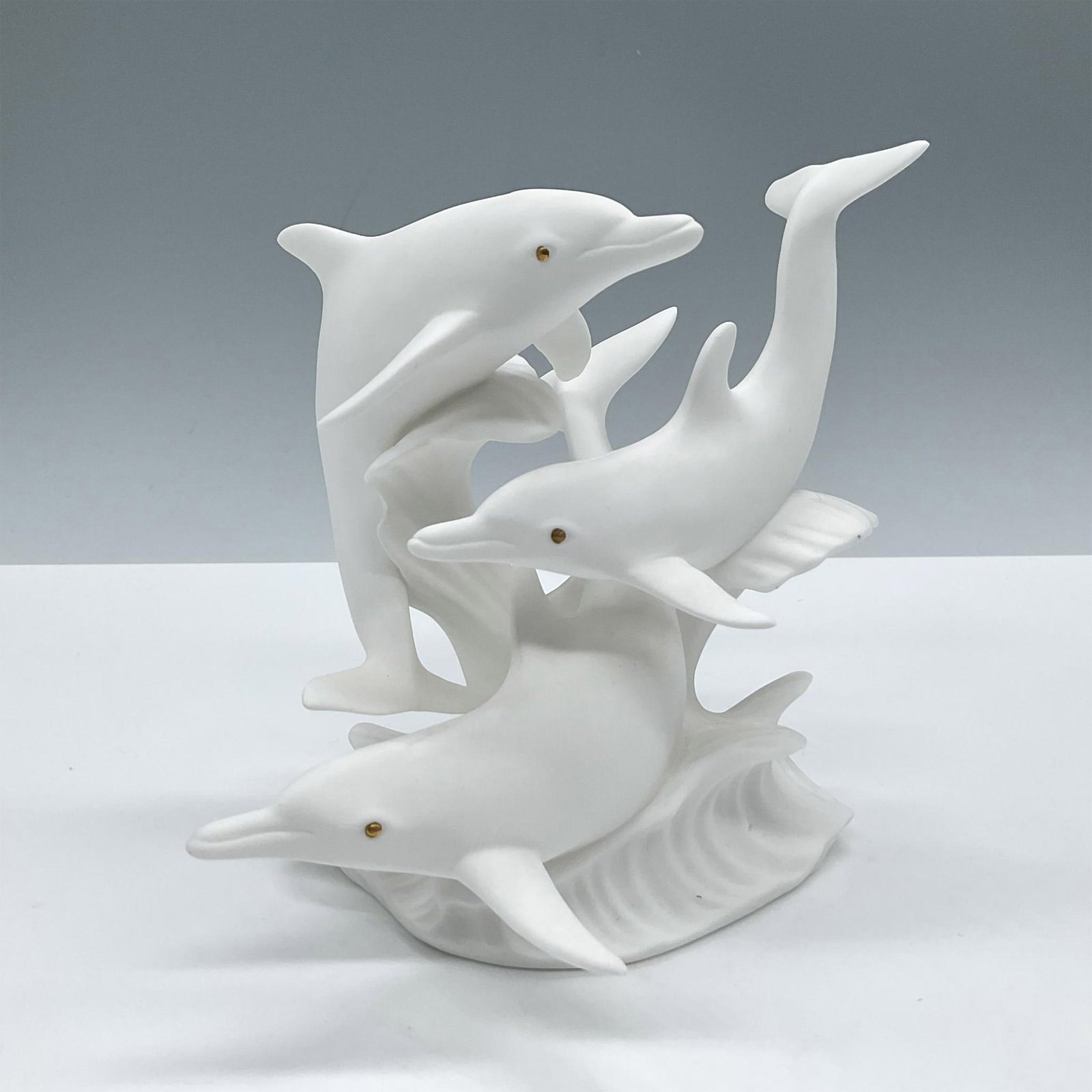 Lenox Fine Bone China Figurine, Flight of the Dolphins: Showcases a dynamic scene of multiple dolphins leaping out of the water in perfect synchronization. Modeled in white matte finish with gold eyes. Lenox backstamp. Issued: 1993 Dimensions: 5''L x 5.5''