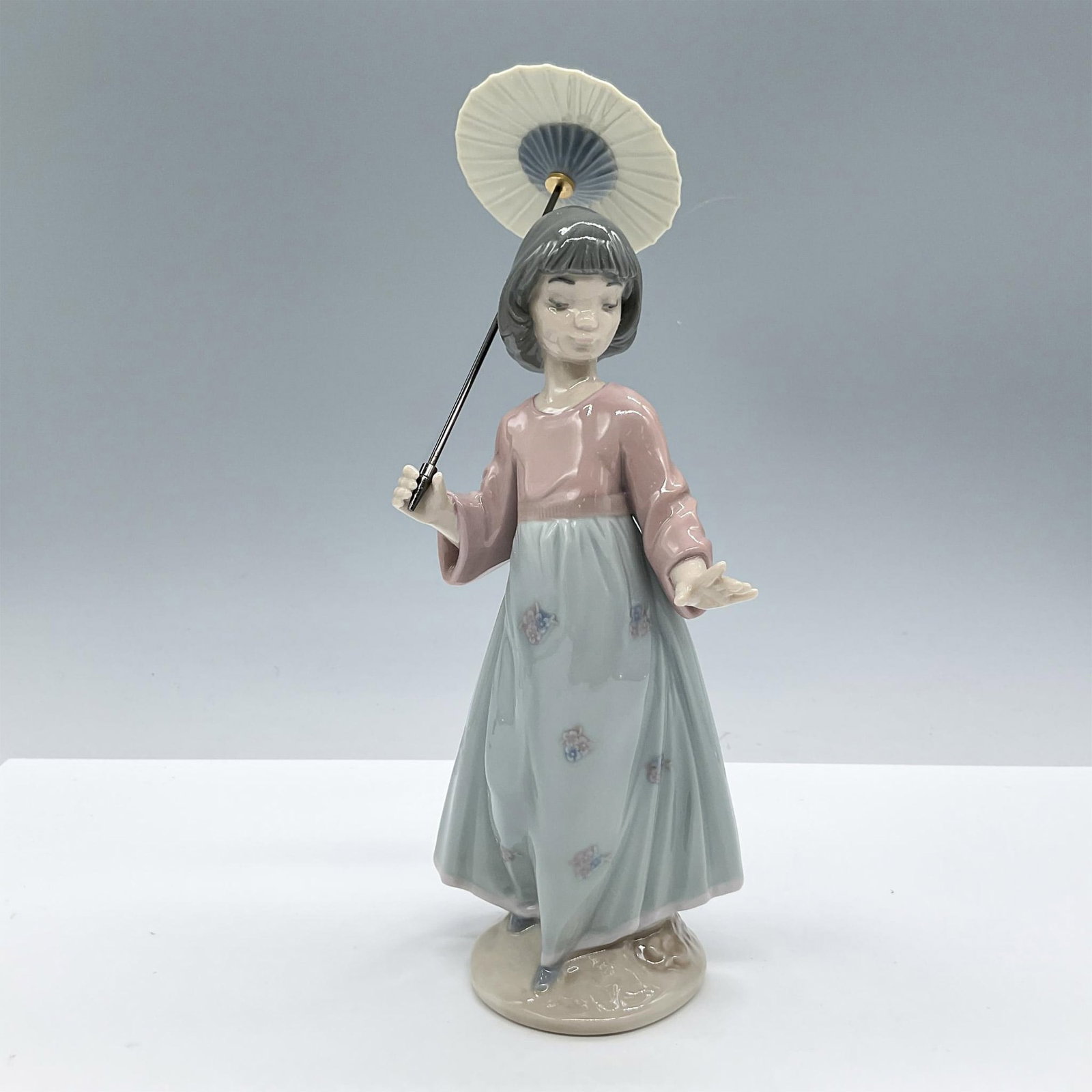 Asian Love 1006156 - Lladro Porcelain Figurine: Glossy finish; Lladro backstamp. Artist: Antonio Ramos Issued: 1994 - 1998 Dimensions: 8.25"H x 4"W Manufacturer: Lladro Country of Origin: Spain