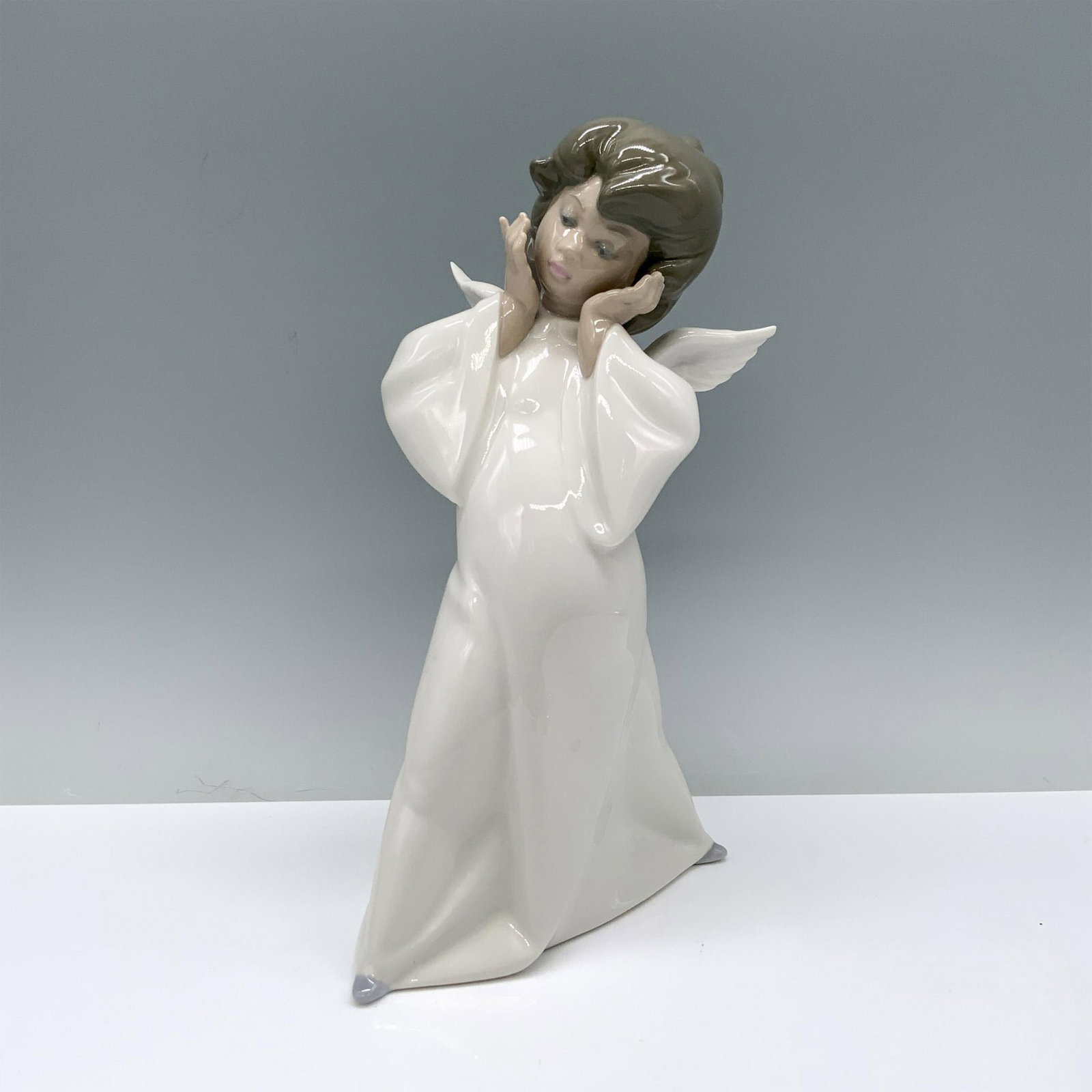 Cherub, Puzzled 1004959 - Lladro Porcelain Figurine: Glossy finish; Lladro backstamp. Artist: Salvador Debon Issued: 1977 Dimensions: 8.75"H x 5"W Manufacturer: Lladro Country of Origin: Spain