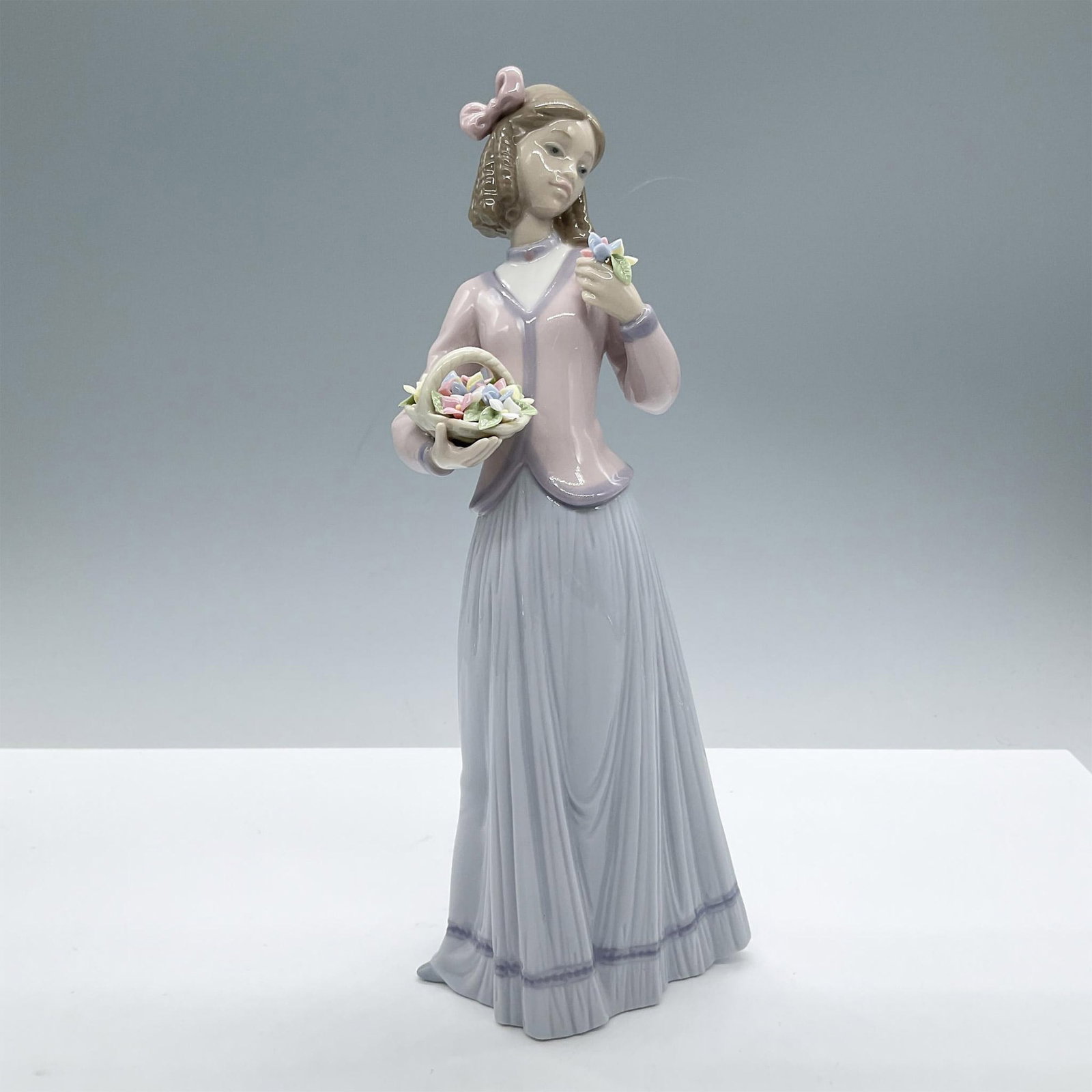 Innocence In Bloom 1007644 - Lladro Porcelain Figurine: Glossy finish; Lladro backstamp. Includes the original box, dimensions: 6.5''L x 11.75''W x 5.5''H. Artist: Jose Puche Issued: 1996 - 1996 Dimensions: 9.75"H x 4.25"W Manufacturer: Lladro Country of O