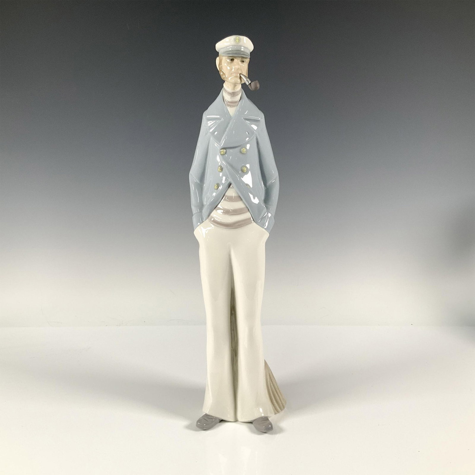 Sea Captain 1004621 - Lladro Porcelain Figurine: Glossy figure of a captain enjoying his pipe after a long day at sea. Lladro backstamp. Artist: Salvador Furio Issued: 1969-1993 Dimensions: 3.50"L x 4"W x 15"H Manufacturer: Lladro Country of Origin: