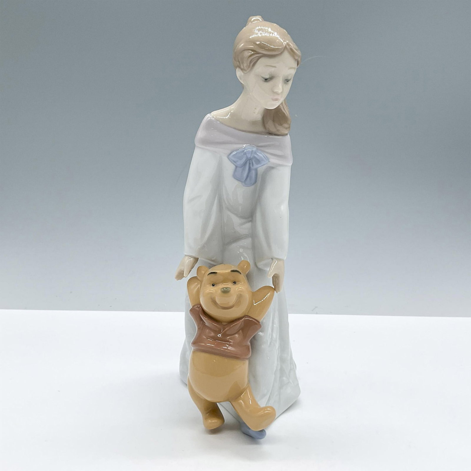Nao Disney Porcelain Figurine, Fun With Winnie The Pooh 1593: A beautiful figure from Nao by Lladro Disney collection, presenting a girl with the iconic character Winnie The Pooh. Nao Disney backstamp. Issued: 20th century Dimensions: 4.25''L x 3.25''W x 9''H Ma