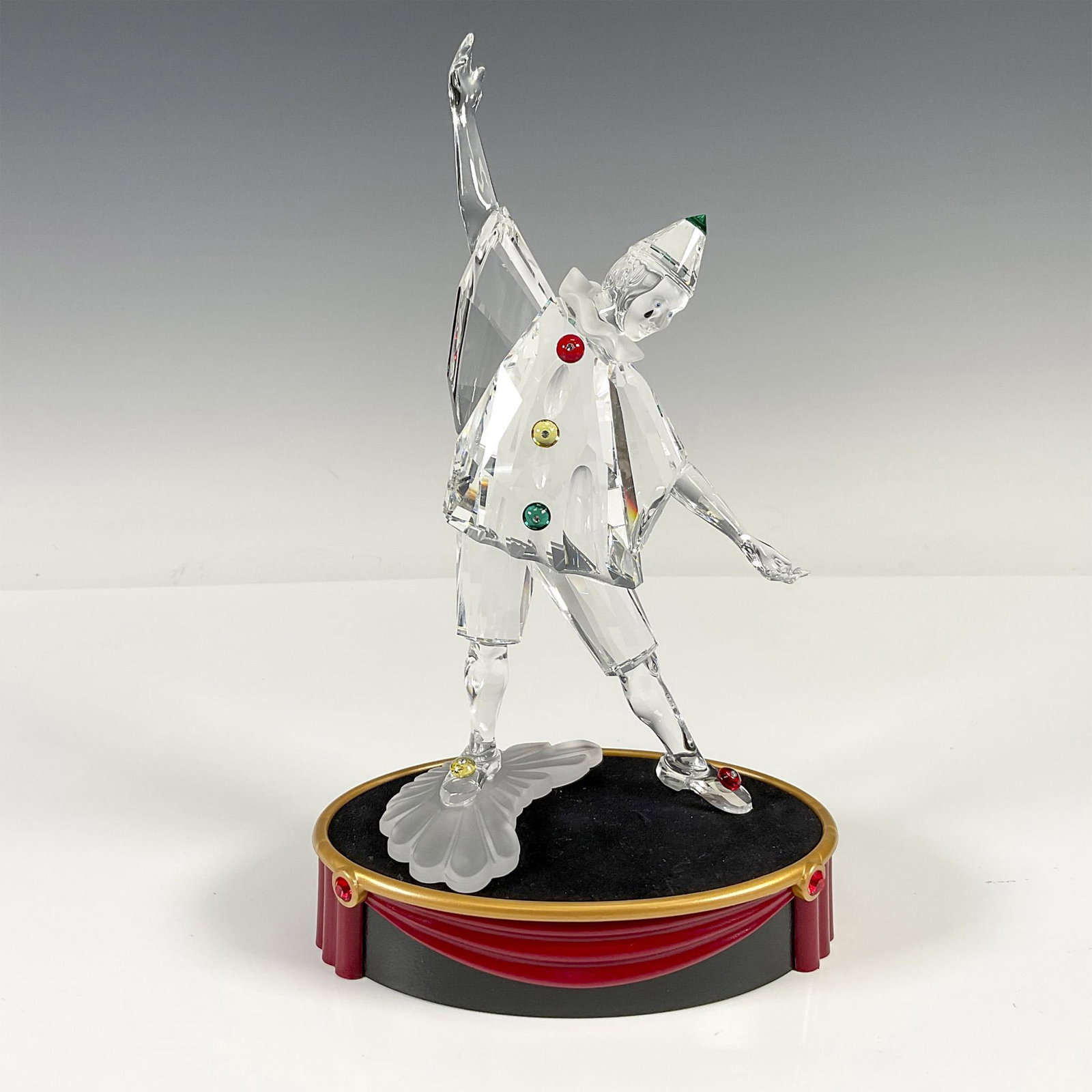 Swarovski Crystal Figurine, 1999 Masquerade Pierrot + Base: First piece of the Masquerade trilogy. This annual edition is created from clear crystal with satin crystal face and collar. His costume is adorned with colored crystal buttons on cloak, hat and shoes