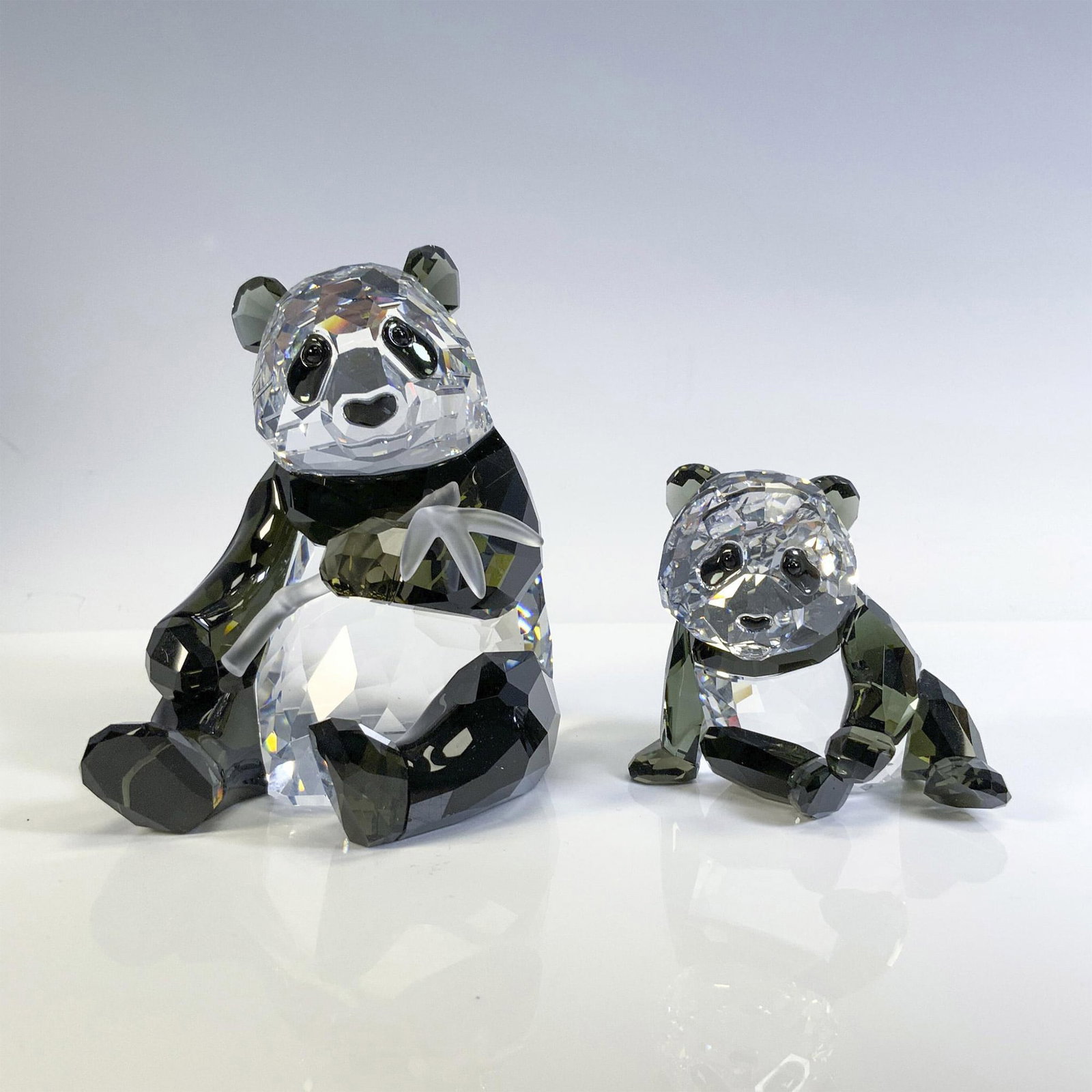 Swarovski Crystal Figurine, Panda Mother and Cub: This Annual Edition piece is part of the Endangered Wildlife Trilogy. Adorable, faceted Panda mother with jet crystal eyes, ears and body, holding satin crystal bamboo. Baby Panda created with clear a
