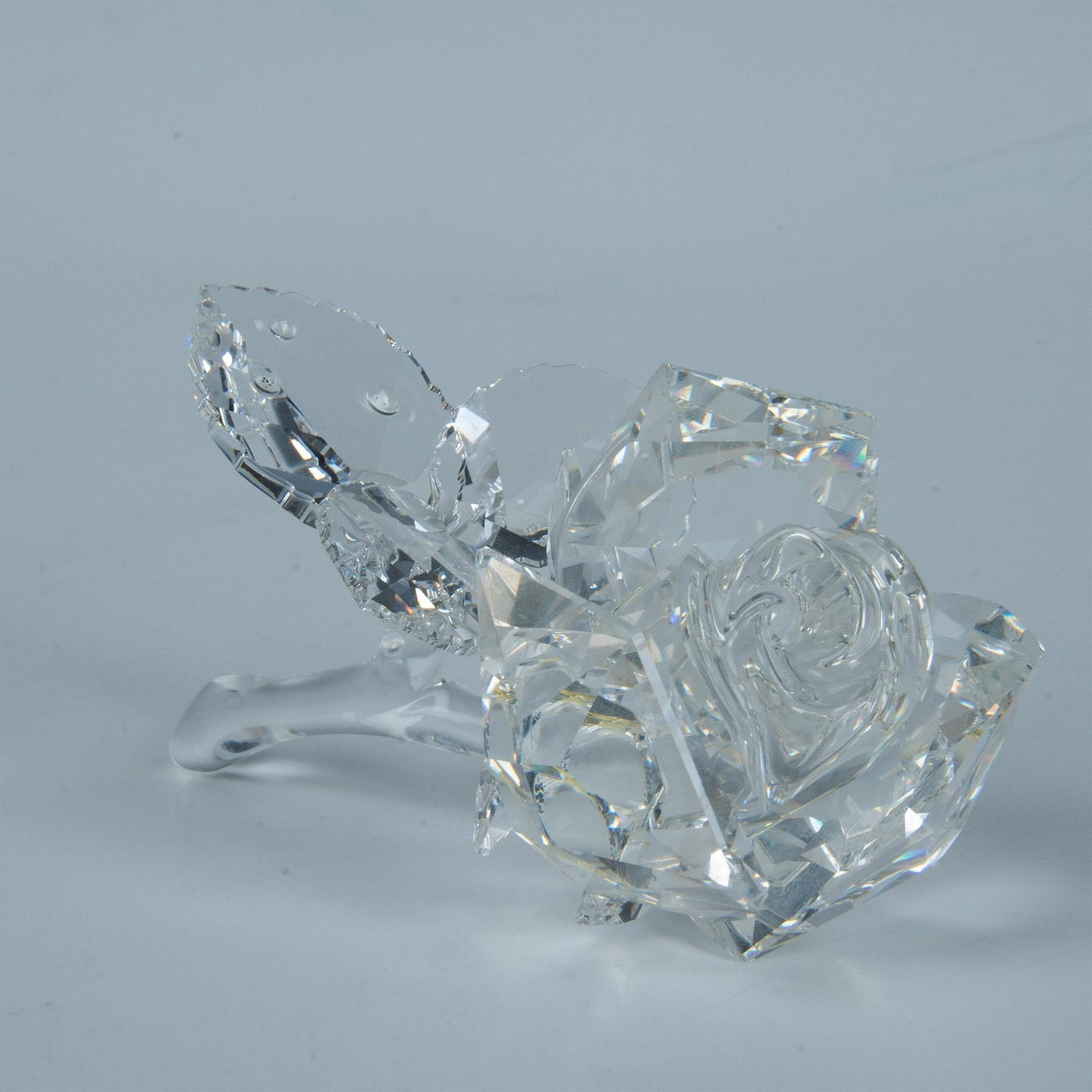 Swarovski Crystal Figurine, Rose Blossom: Clearly defined crystal is part of the Secret Garden theme group. Flower is accurately depicted as blossom opening. Clear crystal stem has leaves reflecting simulated dew with crystal rhinestones. Swa