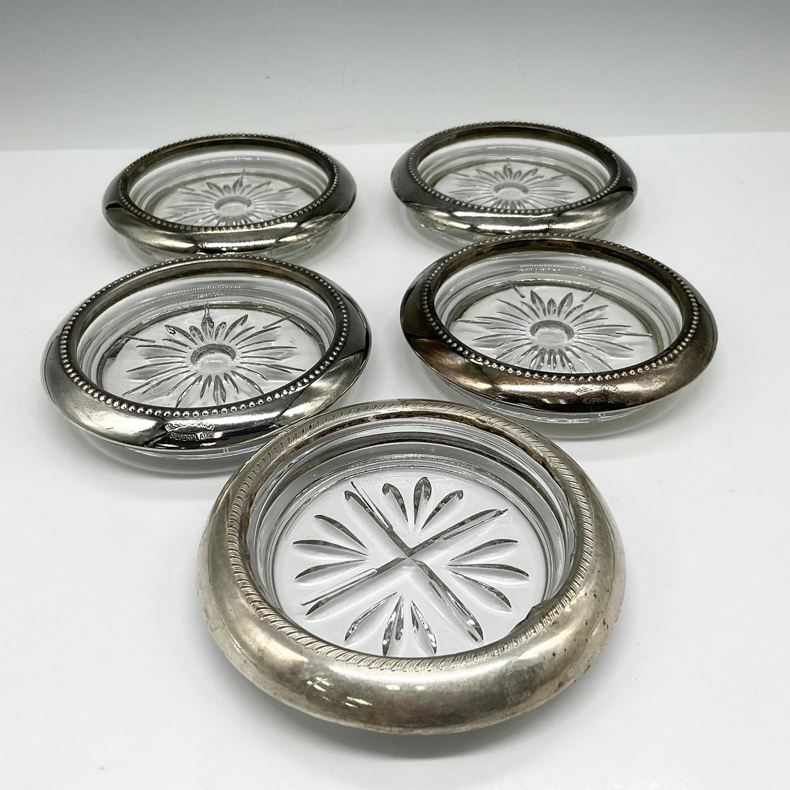5pc Vintage W&S Blackinton Silver Plated Coasters: Four cut glass coasters with flower design and silverplated rim with raised design. W&S Blackinton impressed mark and 1 coaster marked F.B. Rogers Silver with crosscut glass design and silver rim. Iss
