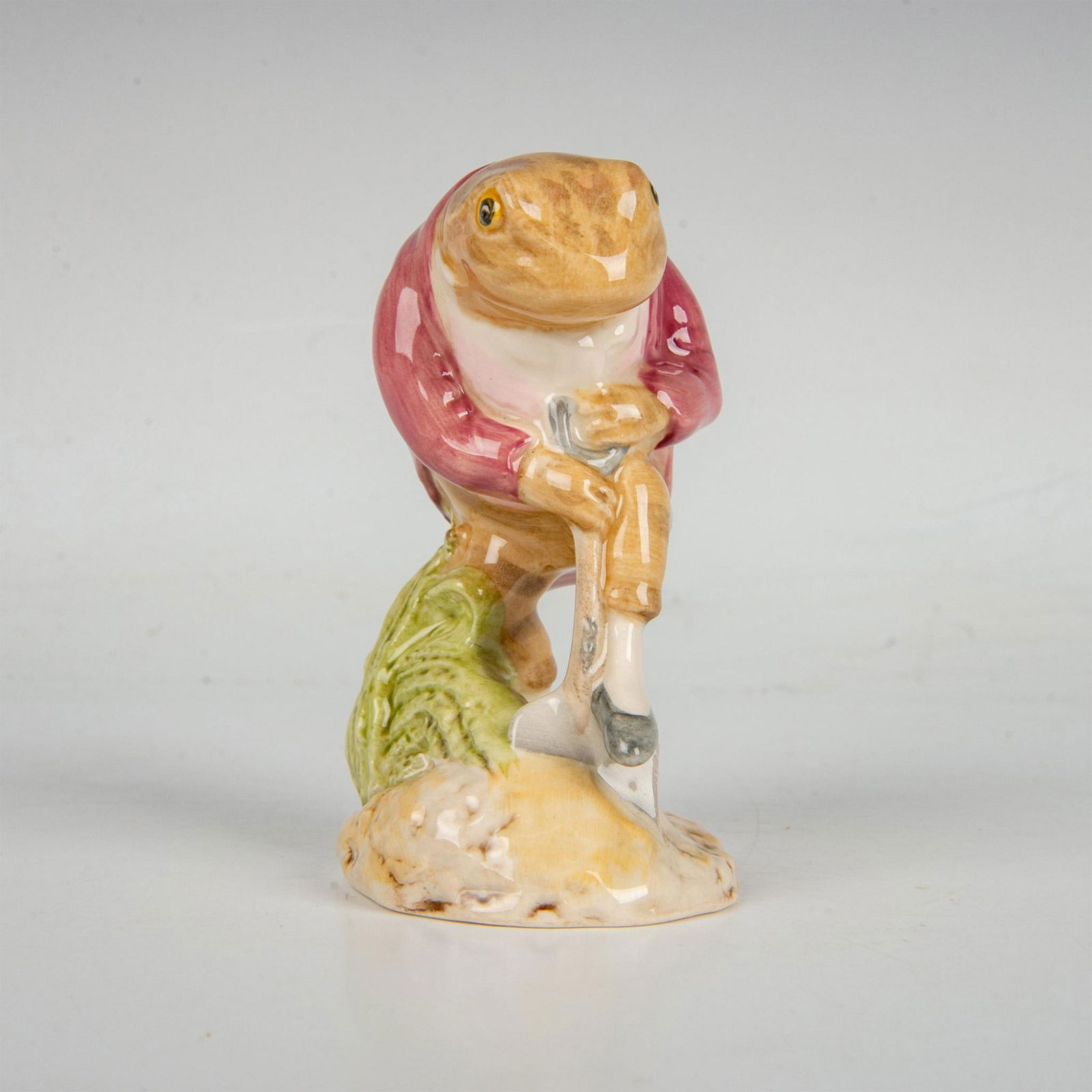 Beswick Beatrix Potter Figurine, Mr. Jeremy Fisher Digging: Hand-painted porcelain figurine modeled as Mr. Jeremy Fisher; a brown frog digging with a shovel under his foot. Beswick Beatrix Potter's backstamp. This item has its original box. Box measures: 3"L x