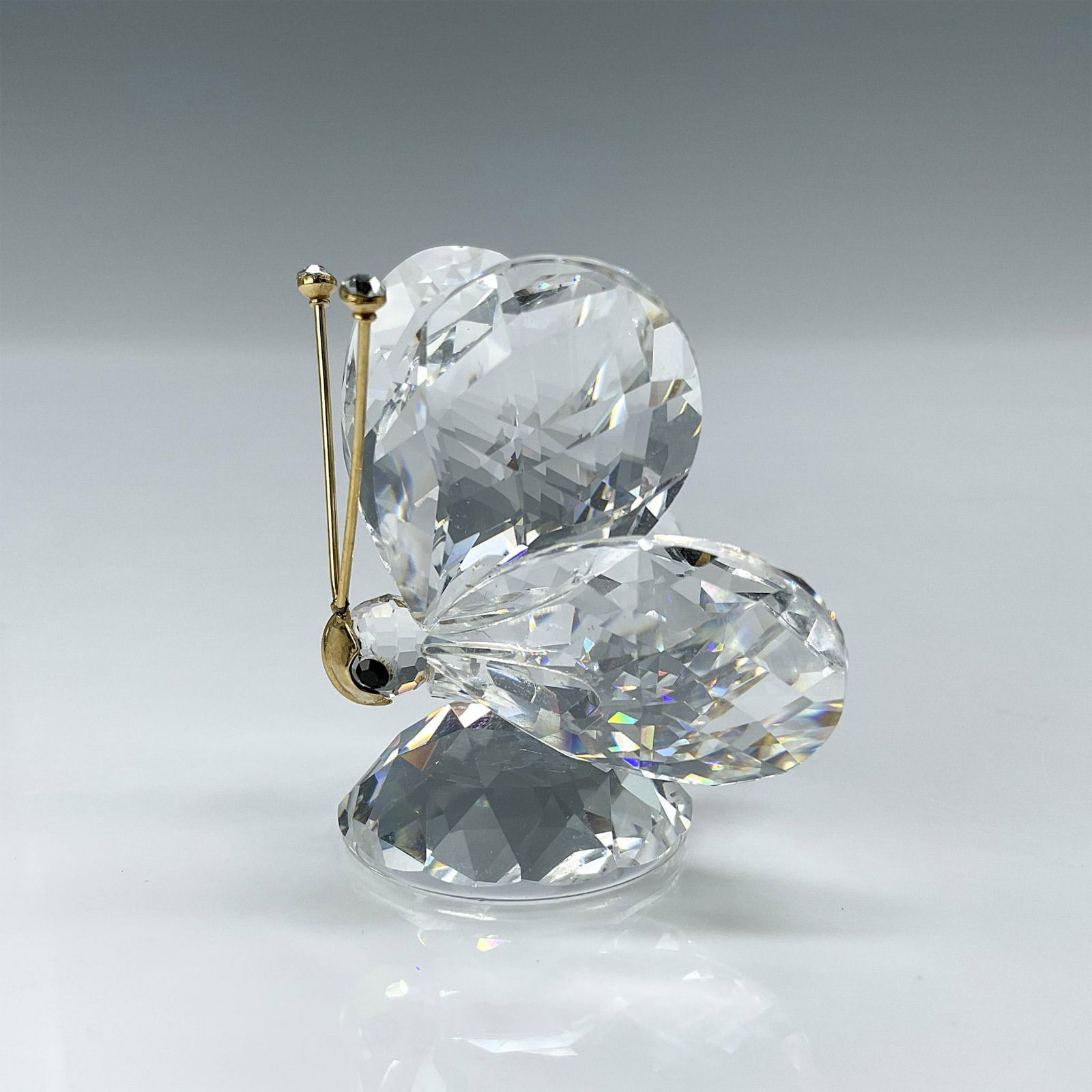Swarovski Crystal Figurine, Butterfly: This version is the third and final one and has gold antenna with a large gold nose which covers most of the face and resembles a mask. It has black eyes, and the tips on the top of the antenna are cl