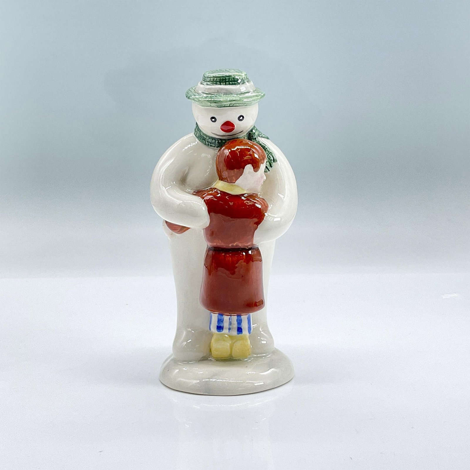 Royal Doulton Figurine, Thank You Snowman DS4: Glazed figure of a boy hugging a snowman in a green hat and scarf. Royal Doulton backstamp. Dimensions: 2.5"L x 2.25"W x 5.25"H Manufacturer: Royal Doulton Country of Origin: England