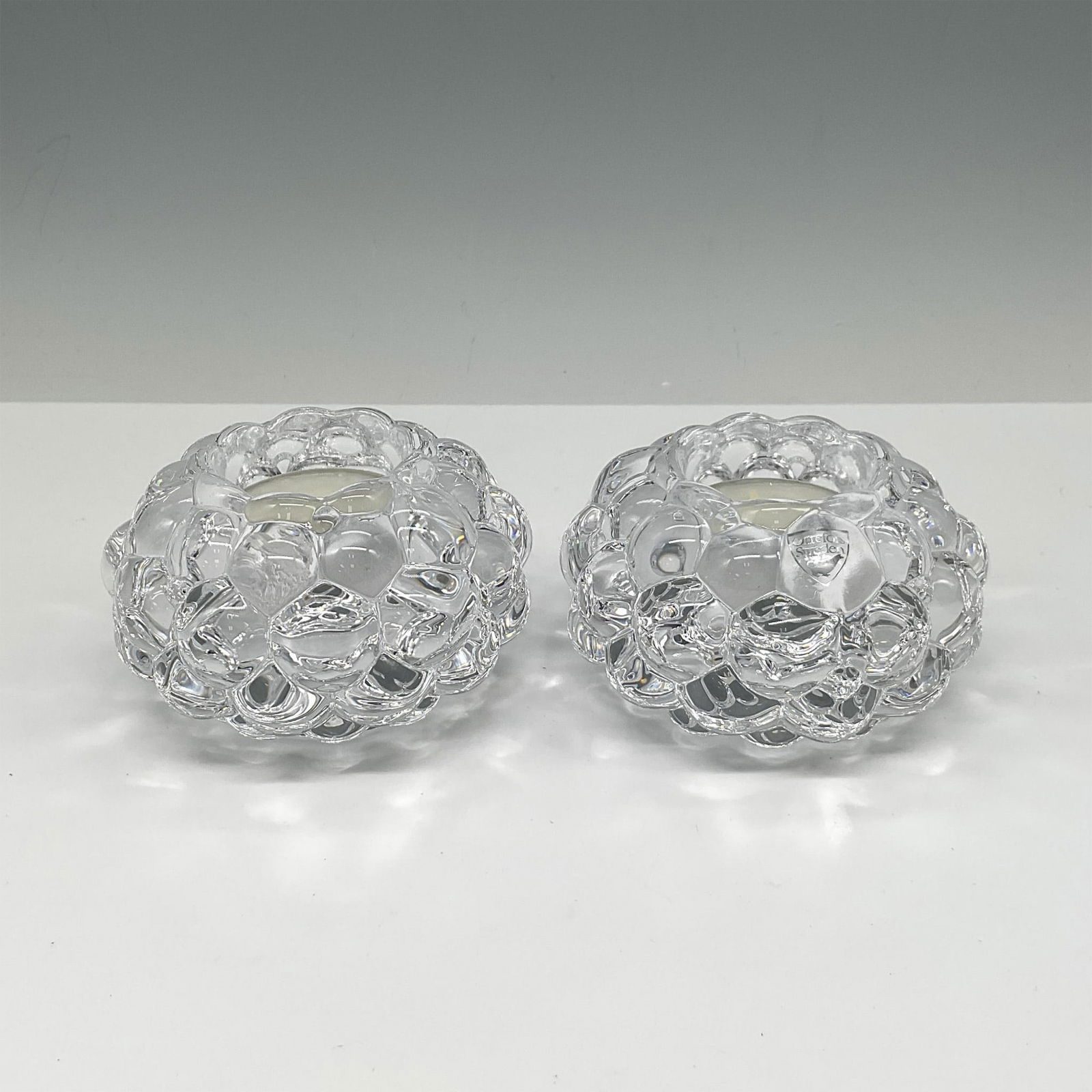 Pair of Orrefors Crystal Hallon-Raspberry Votives: Crystal design of stacked drupelets creates these visually soft and appealing holders. Orrefors mark. This item has its original box: 4"L x 4"W x 3"H. Artist: Anne Nilsson Issued: 21st century Dimensi