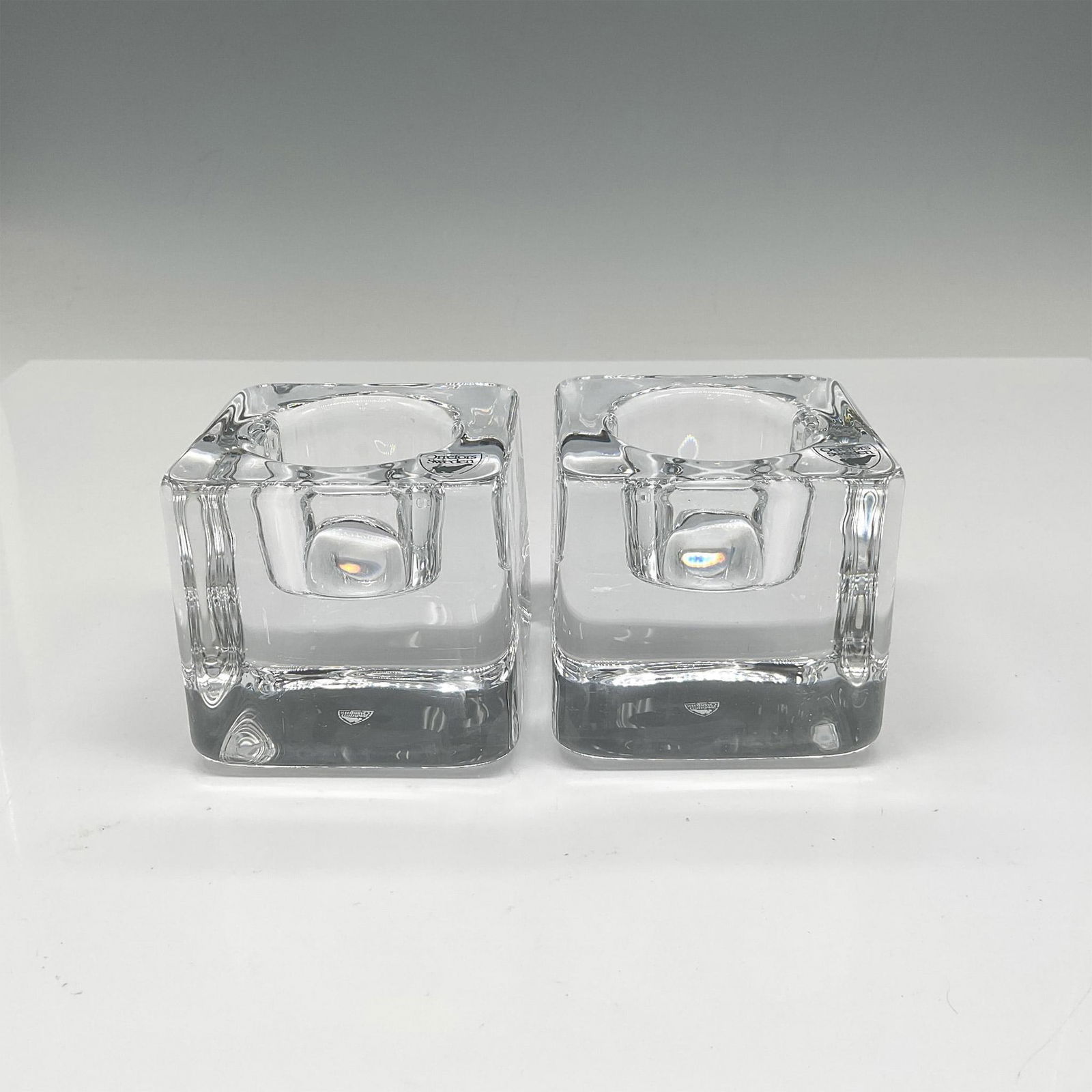 Pair of Orrefors Crystal Nordic Light Ice Cube Votives: Realistic design of ice cube with center holder. Orrefors mark. This item has its original box: 3"L x 3"W x 3"H. Artist: Goran Warff Issued: 21st century Dimensions: 3"L x 3"W x 3"H Manufacturer: Orre