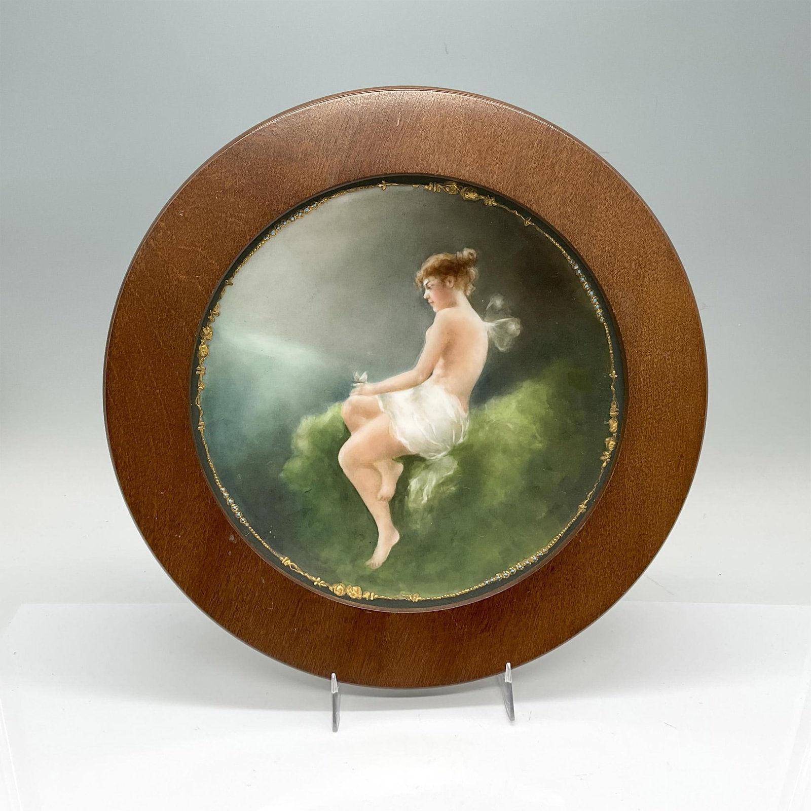 Jean Pouyat Limoges France Porcelain Wall Plate: Housed in a round wooden frame featuring a whimsical serene scene of a partly nude woman, perhaps she is a fairy, admiring a butterfly. Jean Pouyat backstamp. Frame size: 11"W x 1.25"H. Sight size: 8"