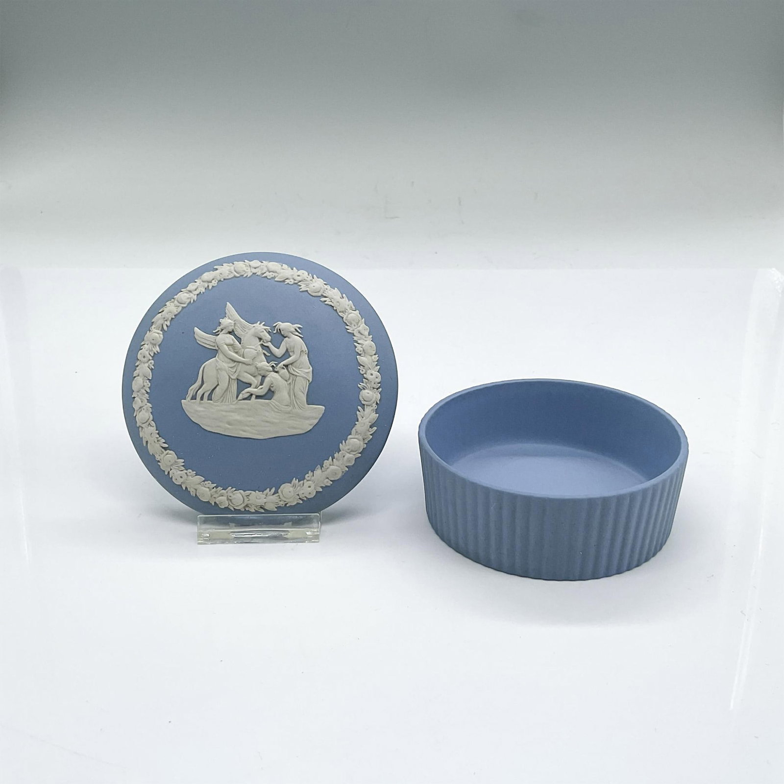 Wedgwood Blue Jasperware Lidded Treasure Box: Matte porcelain round lidded box in Wedgwood blue with neoclassical white sprigged decoration in low-relief. Wedgwood stamp. Dimensions: 1.5"H x 3.25"dia Manufacturer: Wedgwood Country of Origin: Engl
