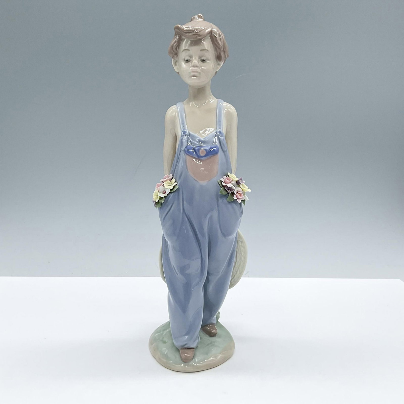 Pocket Full Of Wishes 1007650 - Lladro Porcelain Figurine: Lovely glazed figure of a boy with colorful flowers in his pockets. Lladro backstamp. Artist: Antonio Ramos Issued: 1997 Dimensions: 3.25''L x 3''W x 10.5''H Manufacturer: Lladro Country of Origin: S