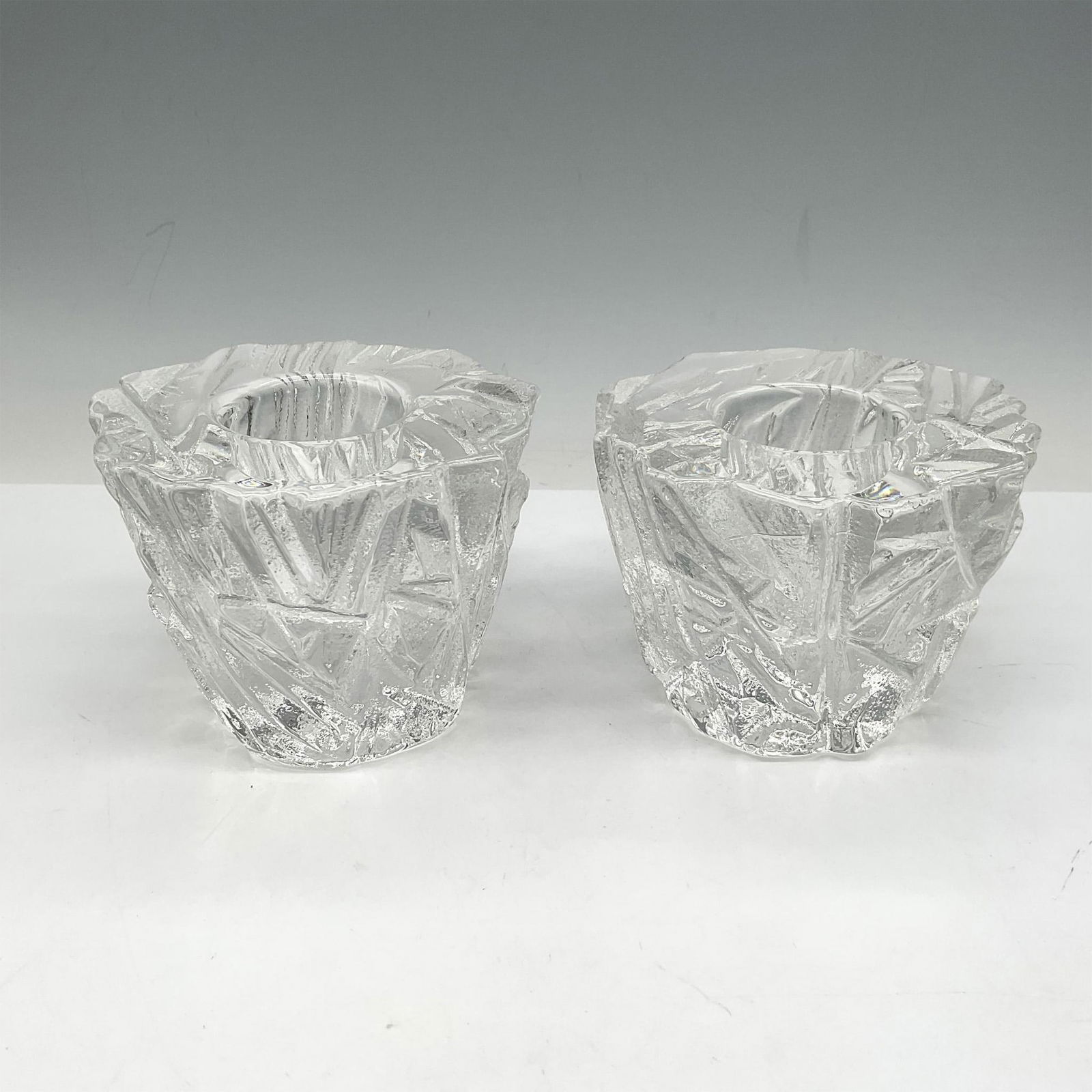 Pair of Orrefors Crystal Votives, Iceberg: This unique crystalized design resembles ice with clear smooth center to hold a candle or tealight. Orrefors acid mark. Issued: 21st century Dimensions: 3.25"H x 4.25" dia. Manufacturer: Orrefors Coun