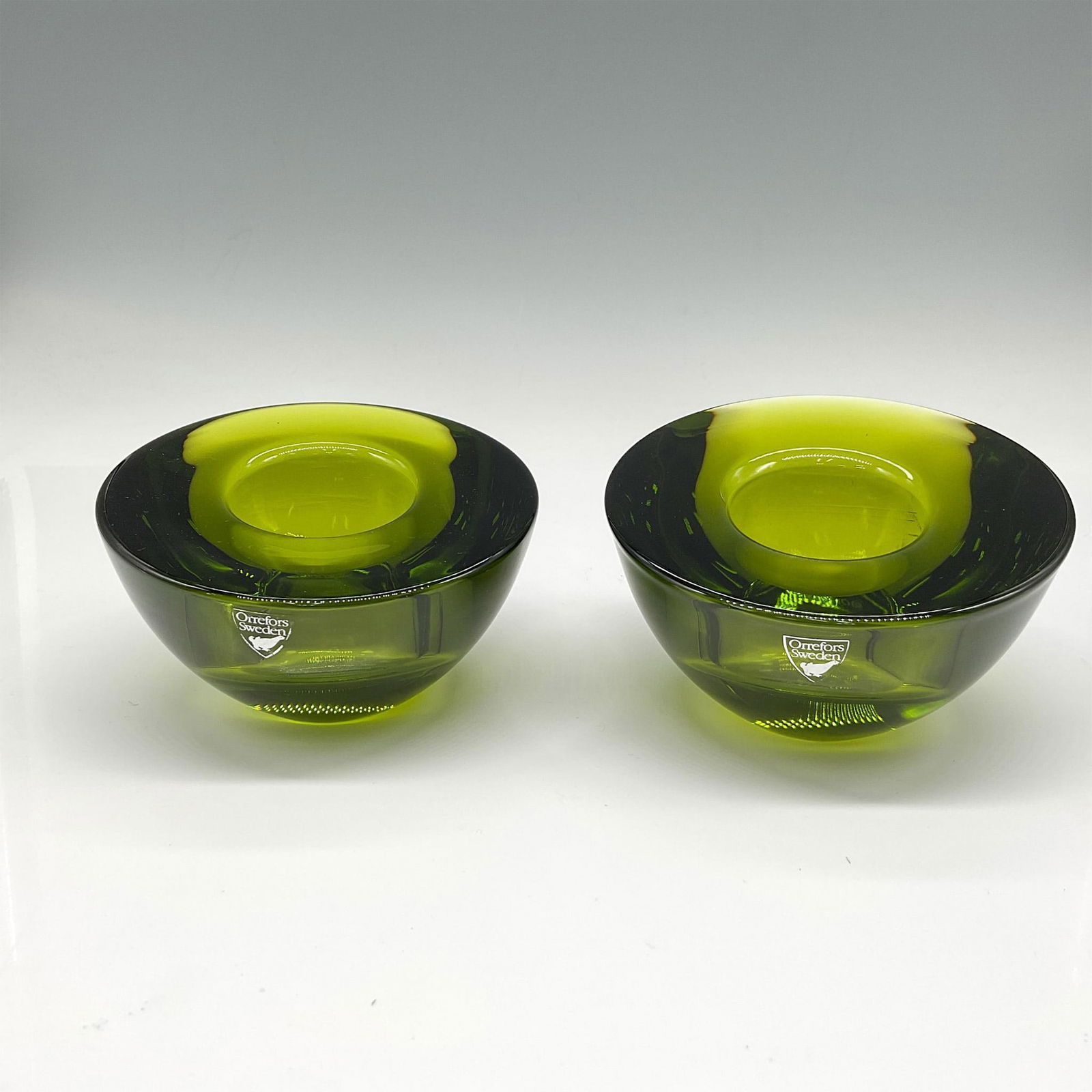 Pair of Orrefors Crystal Lime Votives, Delight: Lovely, simple round design in vibrant green coloration. Orrefors mark. 6544504. This item has its original box: 4"L x 4"W x 3.5"H. Artist: Lena Bergstrom Issued: 21st century Dimensions: 2.5"H x 4" d