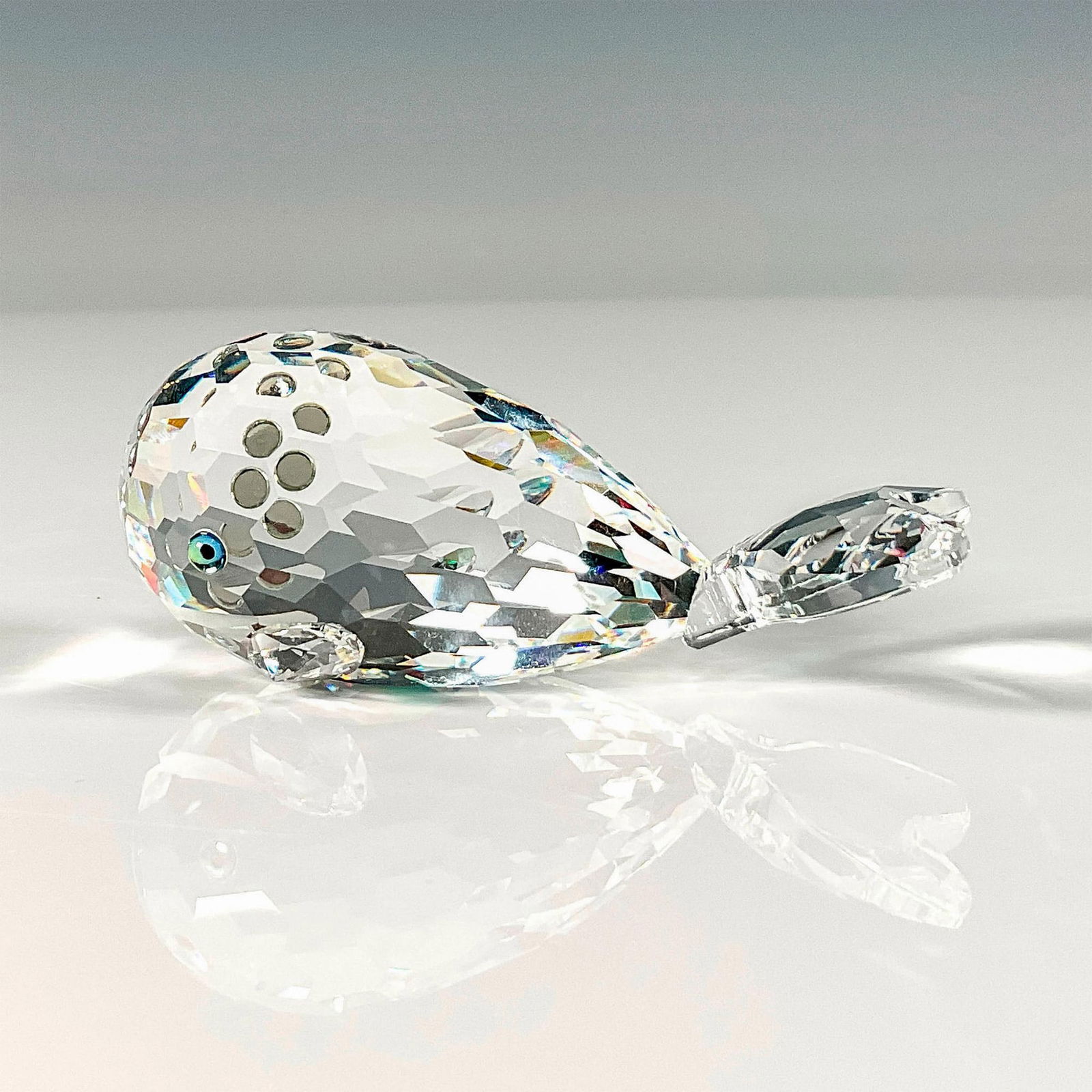 Swarovski Silver Crystal Figurine, Whale: Lead crystal made with green and black eyes and a frosted mouth Also known as Moby Dick or Smiley. Artist signed and dated. Swarovski etched backstamp. This item has its original box. Box measures: 3.