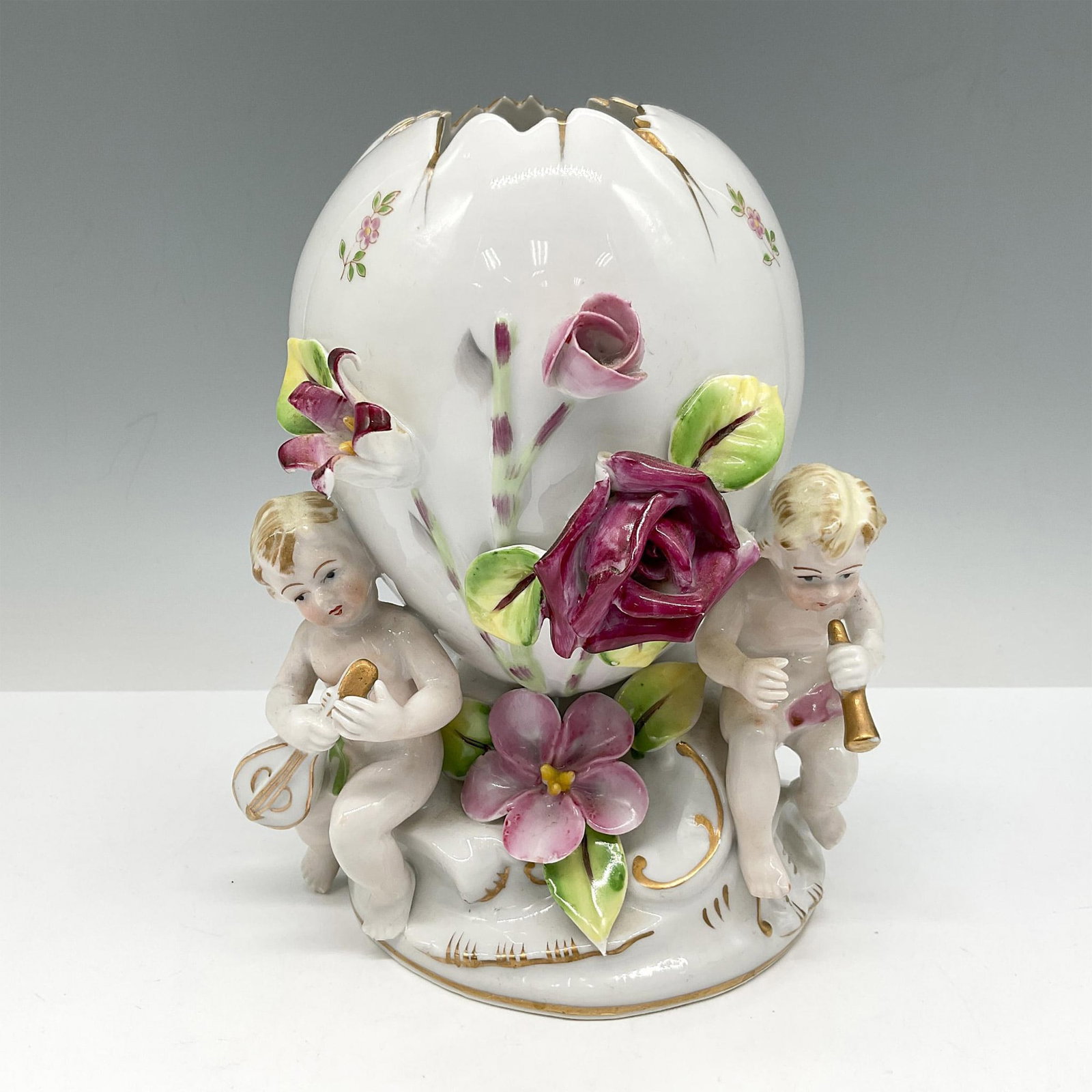 Cherub Porcelain Egg Vase: Possibly German in origin this wonderful white porcelain is intricately and creatively designed with cherubs holding musical instruments, flowers and gilt accents. Flowers are brightly colored in yell