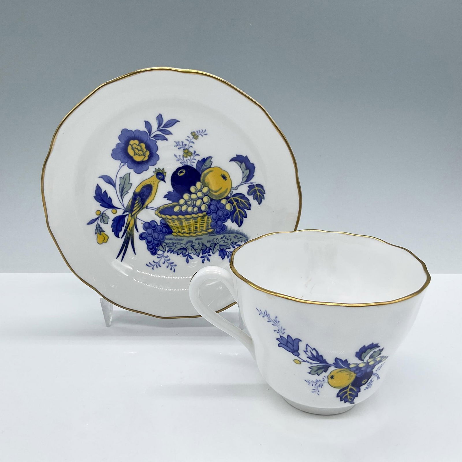 Spode Bone China Tea Cup and Saucer: Features blue and yellow illustrated fruits and birds accented by a gold rim. Spode backstamp. Issued: 20th century Dimensions: Cup: 4.5''L x 3.5''W x 2.75''H; Saucer: 1.25''H x 5.75''dia Manufacturer