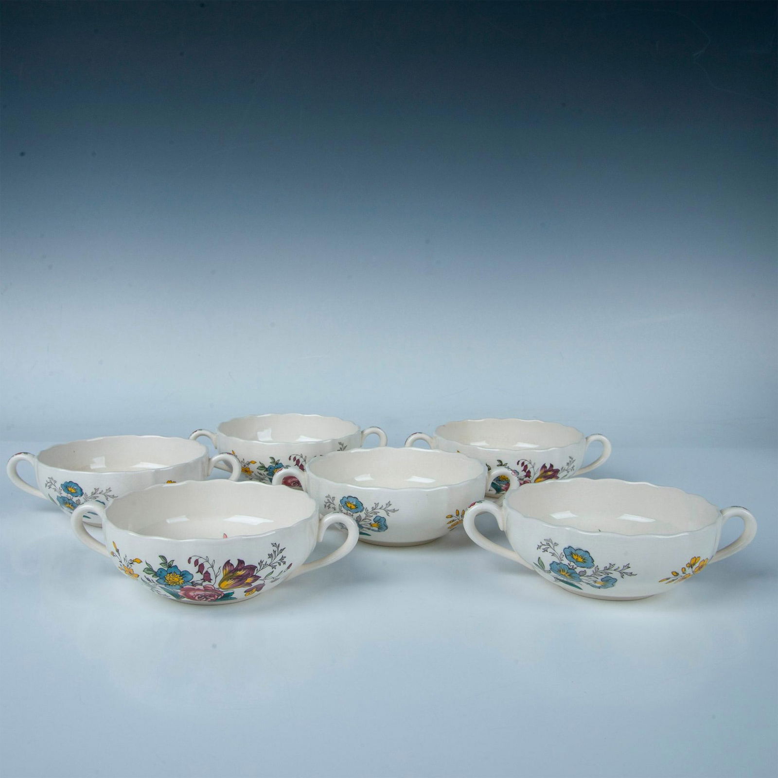 6pc Spode Cream Soup Bowls, Gainsborough: A set of six beige bowls, each featuring two handles and adorned with beautifully detailed floral designs. Spode backstamp. Marked Gainsborough. Dimensions: 7"L x 5"W x 2"H Manufacturer: Spode Country